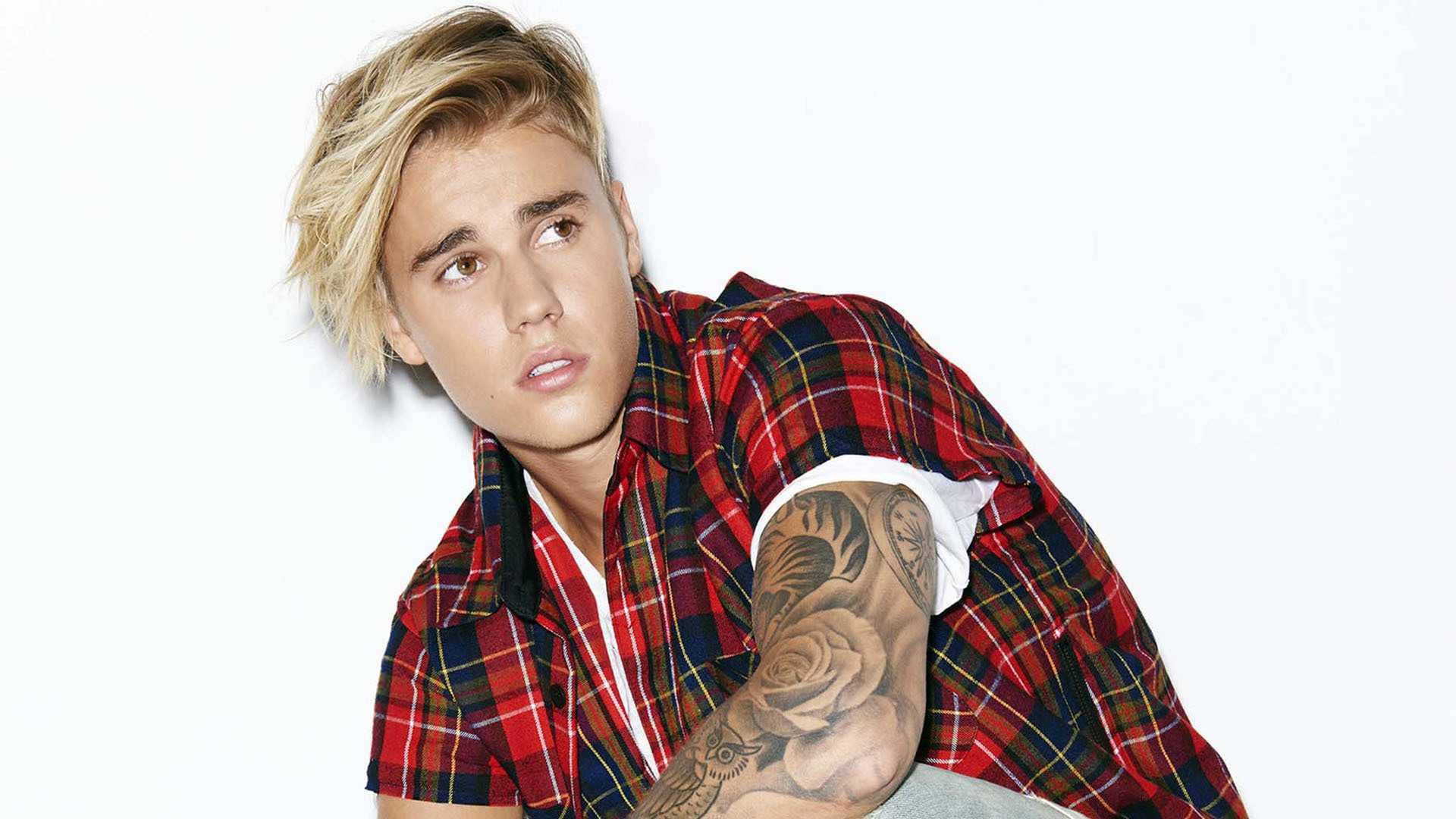 小賈斯汀 桌布 壁紙 — 金髮紋身年輕男子穿著紅色格紋襯衫，背景為純白色。
