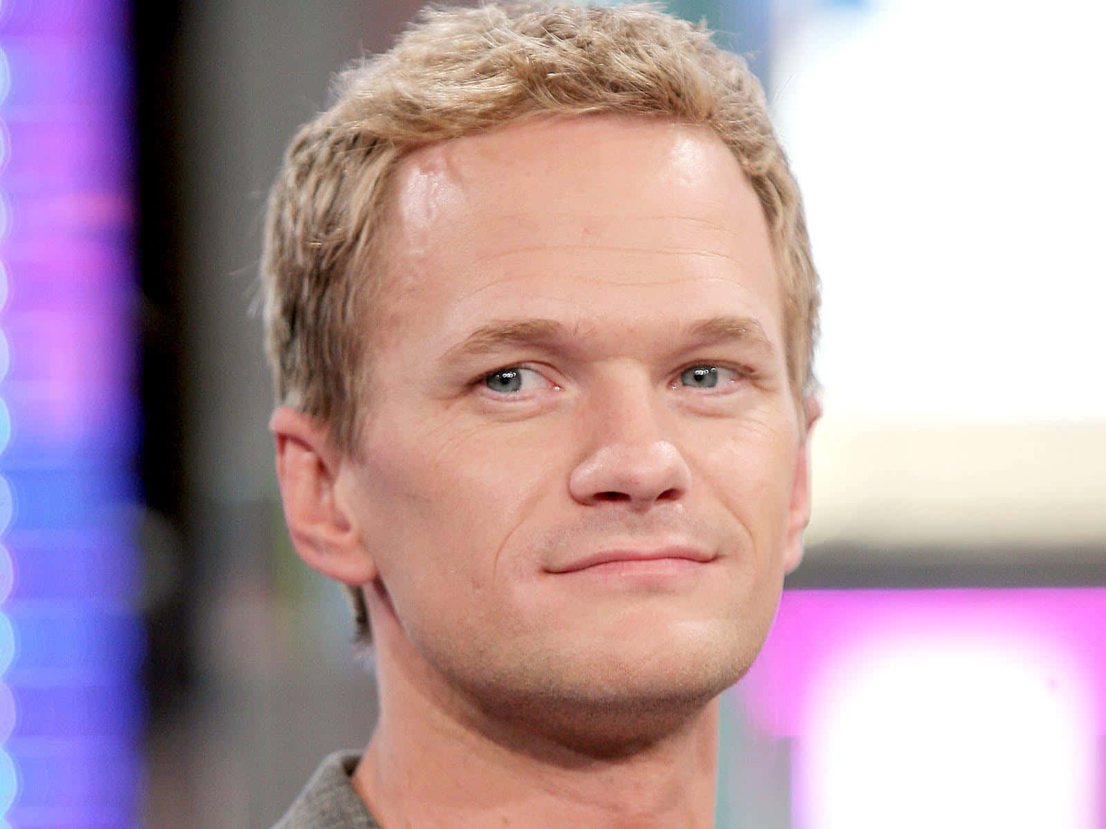 neil patrick harris 桌布 壁紙 — 金髮藍眼男子的特寫肖像，在模糊彩色背景前微微微笑。