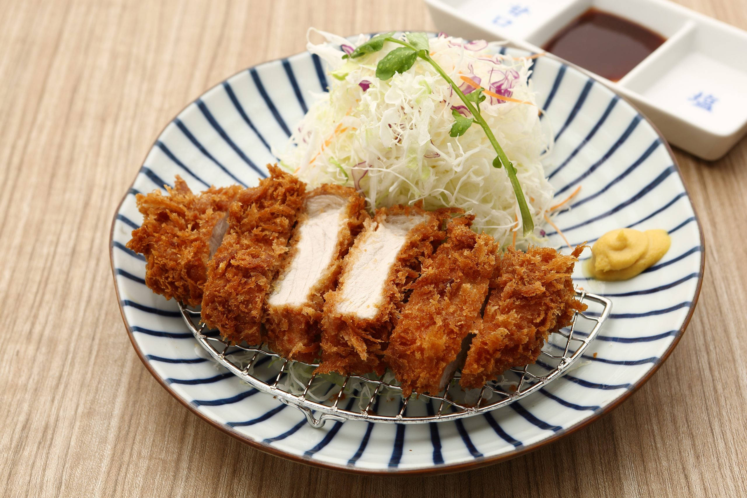 Food Photography 桌布 壁紙 — 金黃色切片吉列豬排放在條紋盤上，配上高麗菜絲和芥末蛋黃醬。