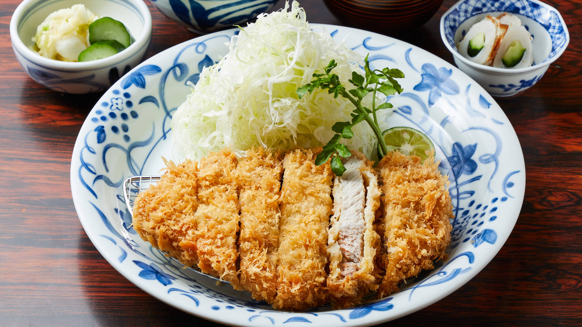 Food Photography 桌布 壁紙 — 金黃色切片炸豬排配高麗菜絲和裝飾，放在藍色花卉盤上。