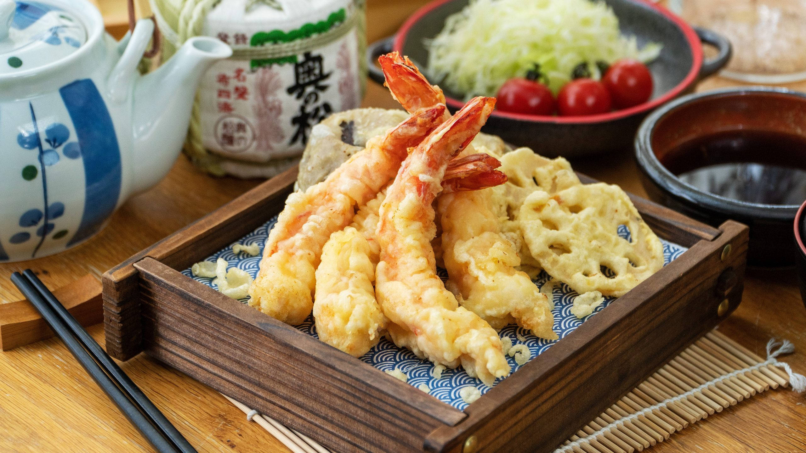 shrimp 桌布 壁紙 — 金黃色天婦羅蝦和蓮藕，盛裝在木盒中，搭配小菜和茶，置於竹蓆上。