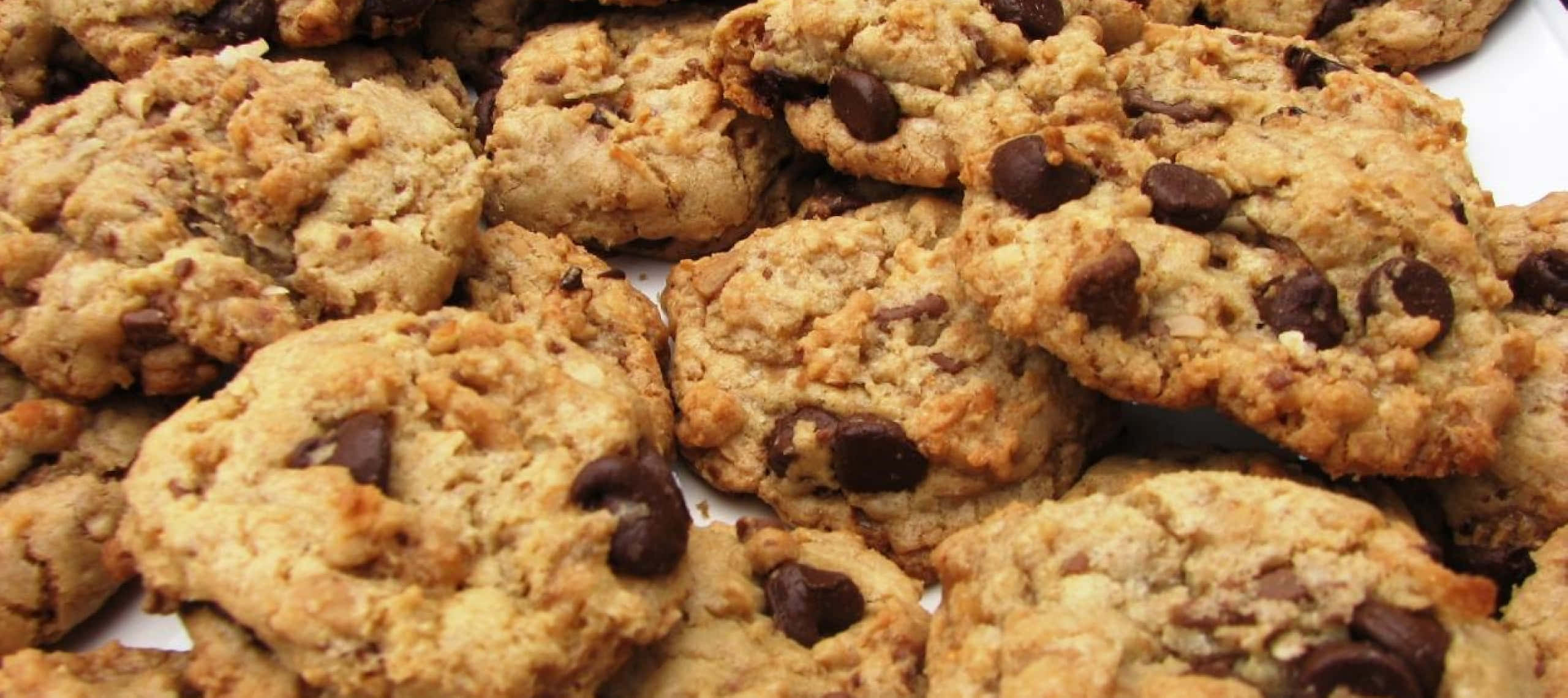 1440p Cookies 桌布 壁紙 — 金黃色巧克力曲奇餅的特寫，堆疊得高高的，上面有融化的巧克力塊和燕麥片。
