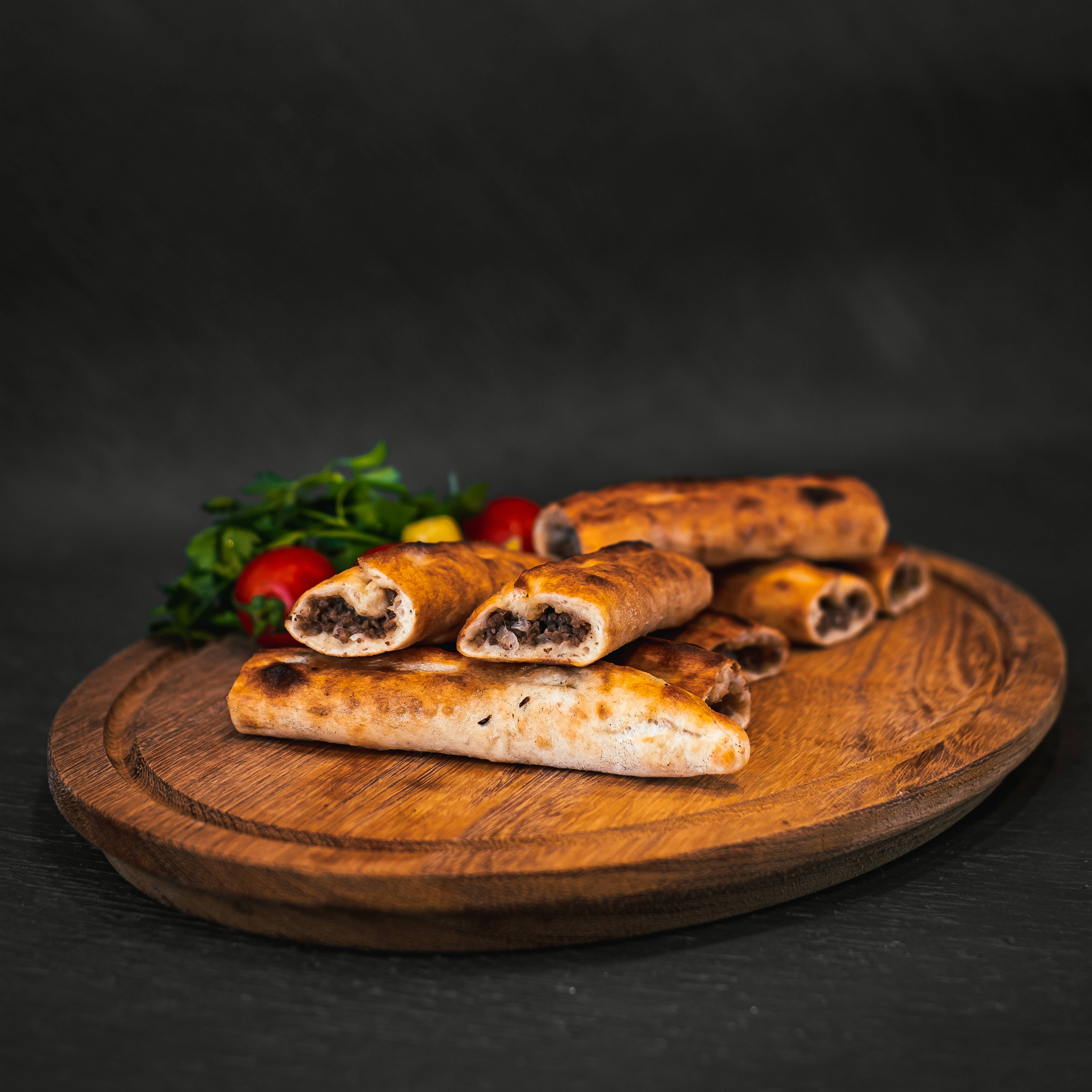 Bread 桌布 壁紙 — 金黃色捲狀糕點搭配深色餡料，放置在質樸木板上，旁邊有新鮮香草和櫻桃番茄。
