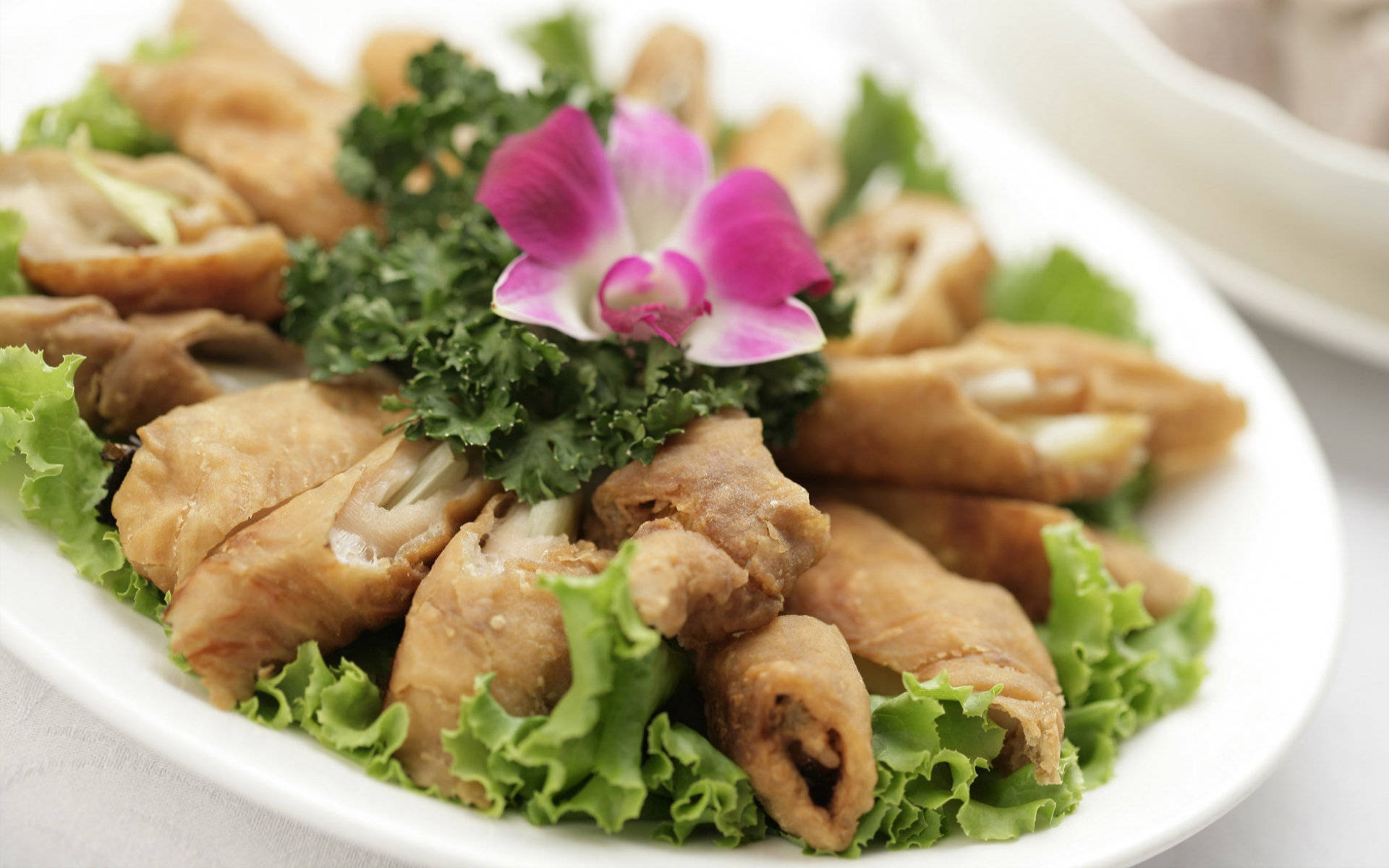 4K Food 桌布 壁紙 — 金黃色炸卷放在脆綠生菜上，搭配鮮豔的粉紅蘭花裝飾。
