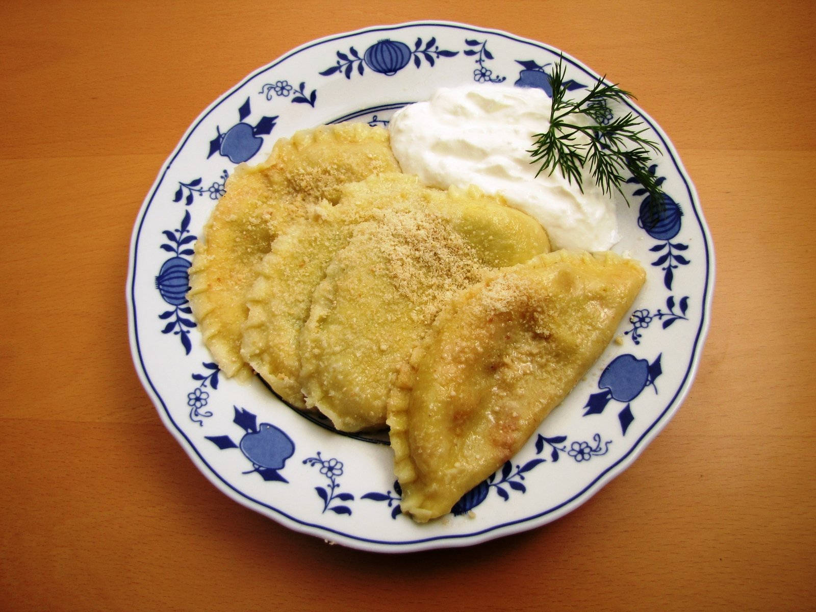 Food Photography 桌布 壁紙 — 金黃色炸波蘭餃子撒上麵包粉，配上酸奶油和蒔蘿，放在藍色花卉圖案盤子上。
