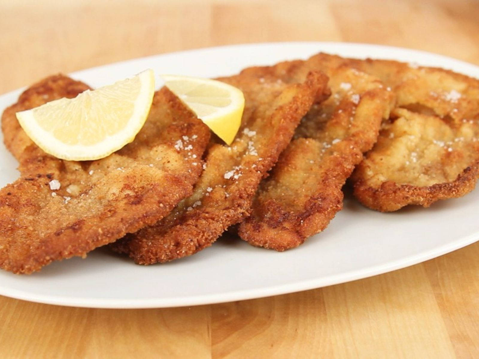 Delicious Food 桌布 壁紙 — 金黃色炸肉排配鹽和檸檬角，放在木桌上的白色盤子上。
