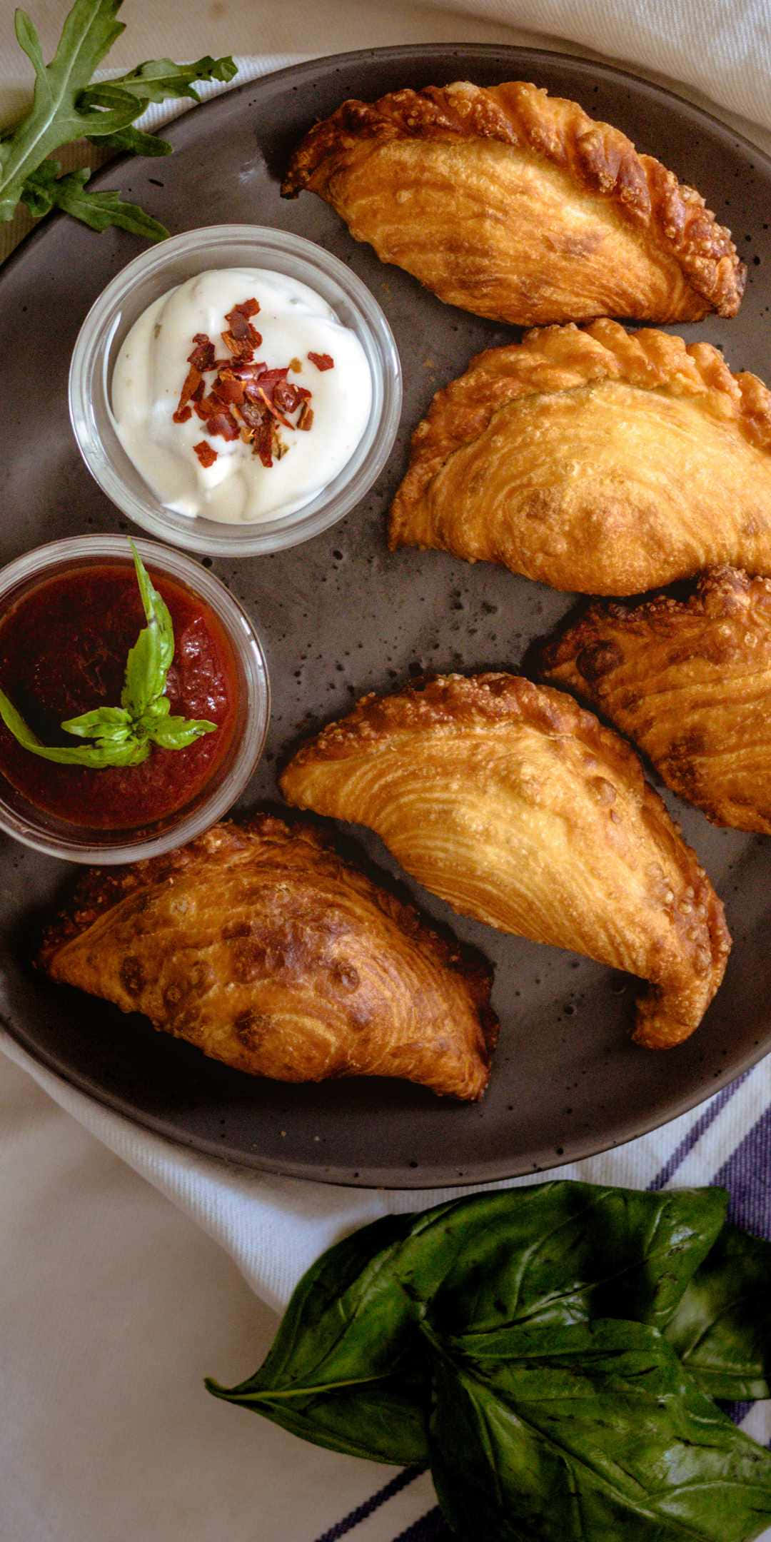 Pie 桌布 壁紙 — 金黃色炸肉餡捲餅放在深色盤子上，搭配奶油蘸醬和鮮紅色莎莎醬，並以新鮮羅勒裝飾。
