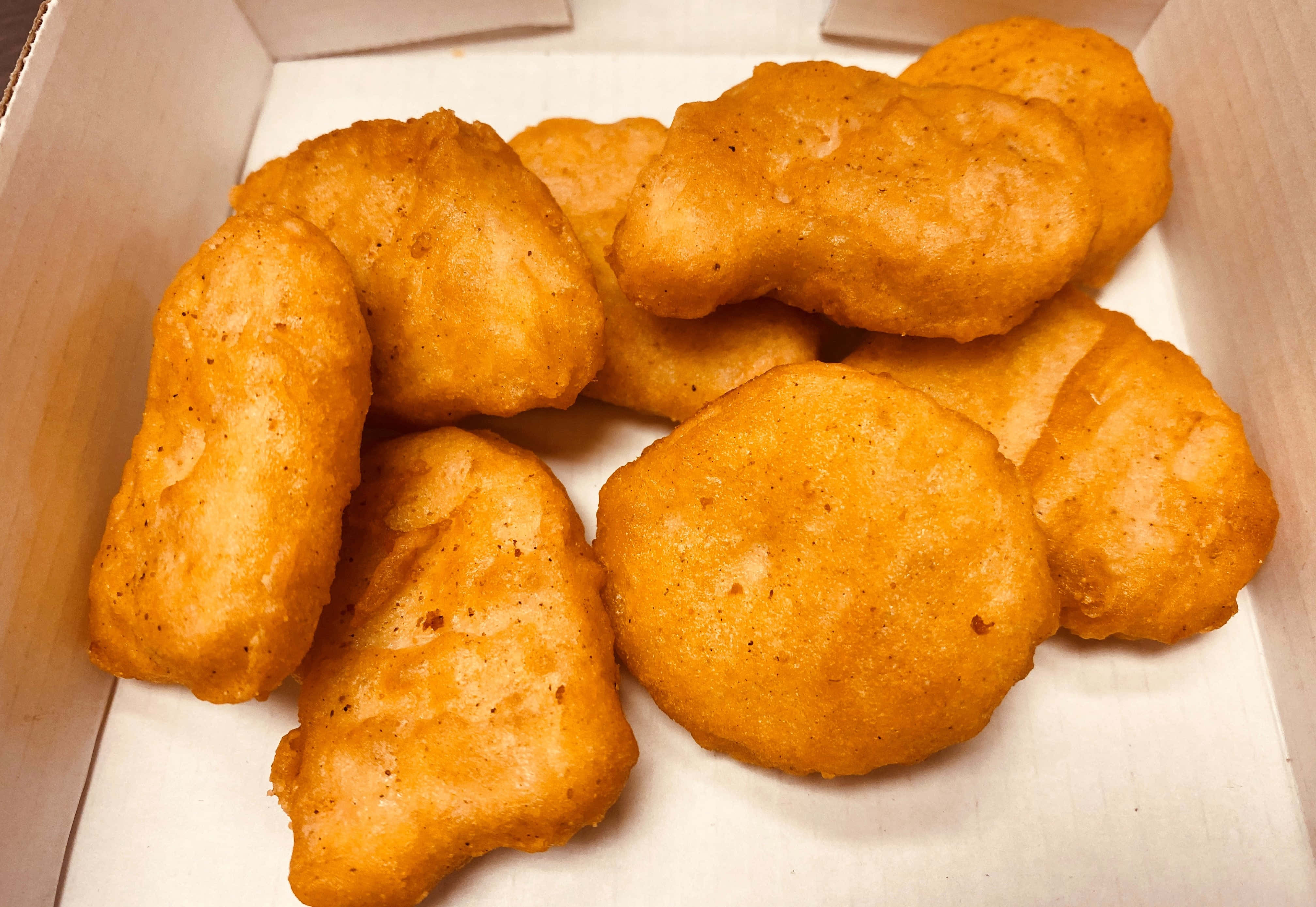 Chicken 桌布 壁紙 — 金黃色炸雞塊堆疊在白色紙板盒中，帶有酥脆的麵包糠外層。