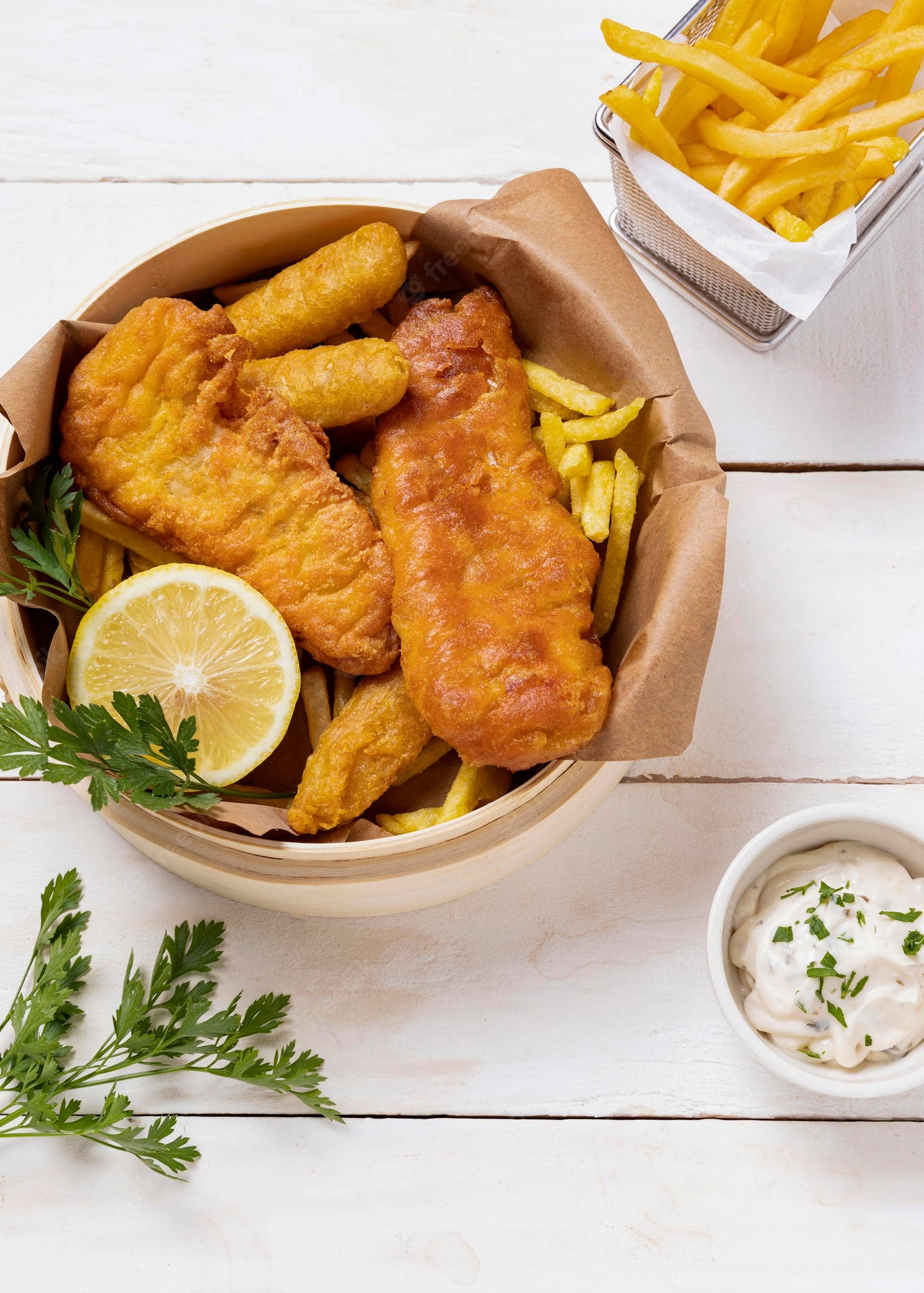 Delicious Food 桌布 壁紙 — 金黃色炸魚薯條盛載於鋪有紙的碗中，配以檸檬、歐芹和塔塔醬，放在白色木桌上。