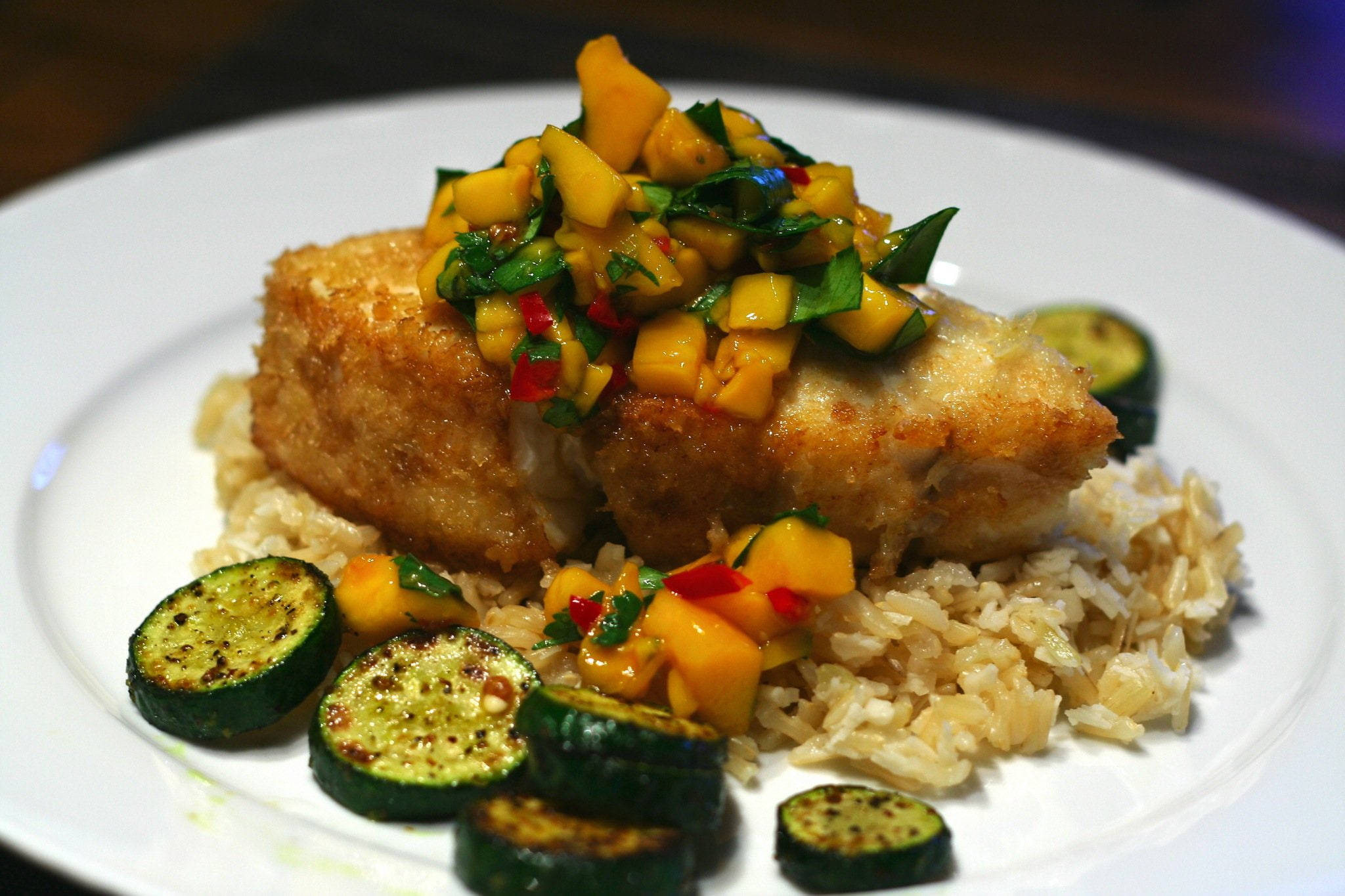Halibut 桌布 壁紙 — 金黃色炸魚配上鮮豔芒果莎莎醬和烤櫛瓜，放在米飯上。