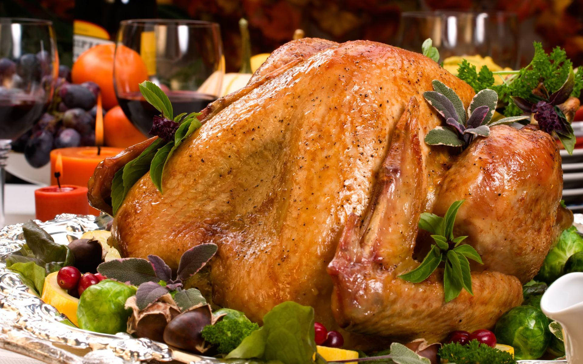 Turkey Happy Thanksgiving 桌布 壁紙 — 金黃色烤火雞為中心，飾以香草和蔓越莓，擺放在節日盛宴餐桌上。