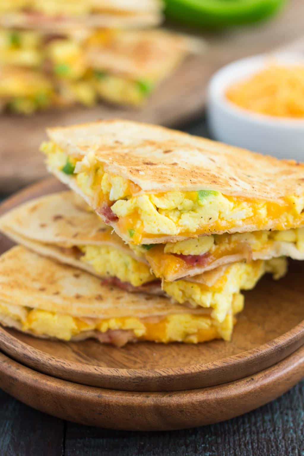 早餐 桌布 壁紙 — 金黃色烤起司三明治，內含炒蛋、培根和融化切達起司，堆疊在木盤上。