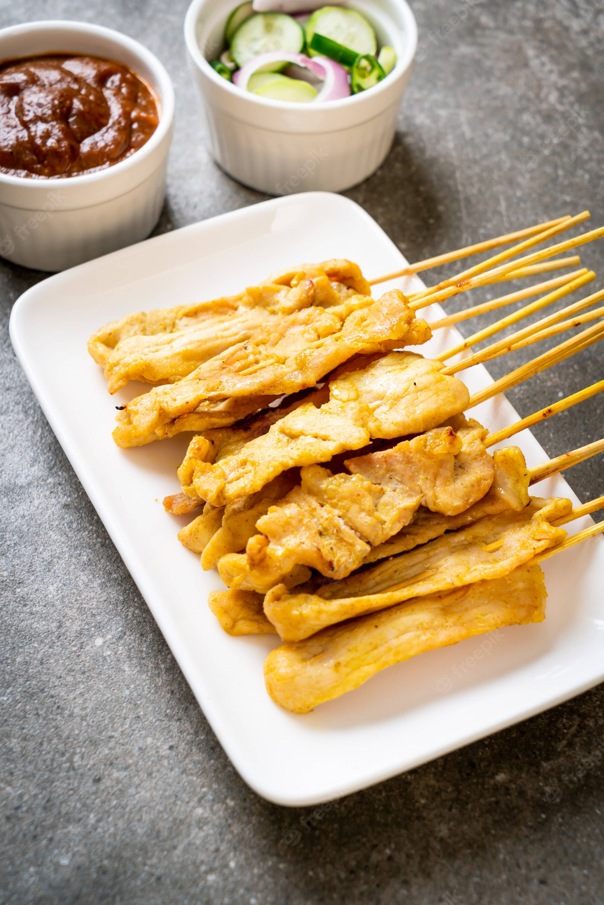 Food Photography 桌布 壁紙 — 金黃色烤雞肉沙爹串，盛裝在白色盤子上，搭配辣花生醬和黃瓜洋蔥酸辣醬。