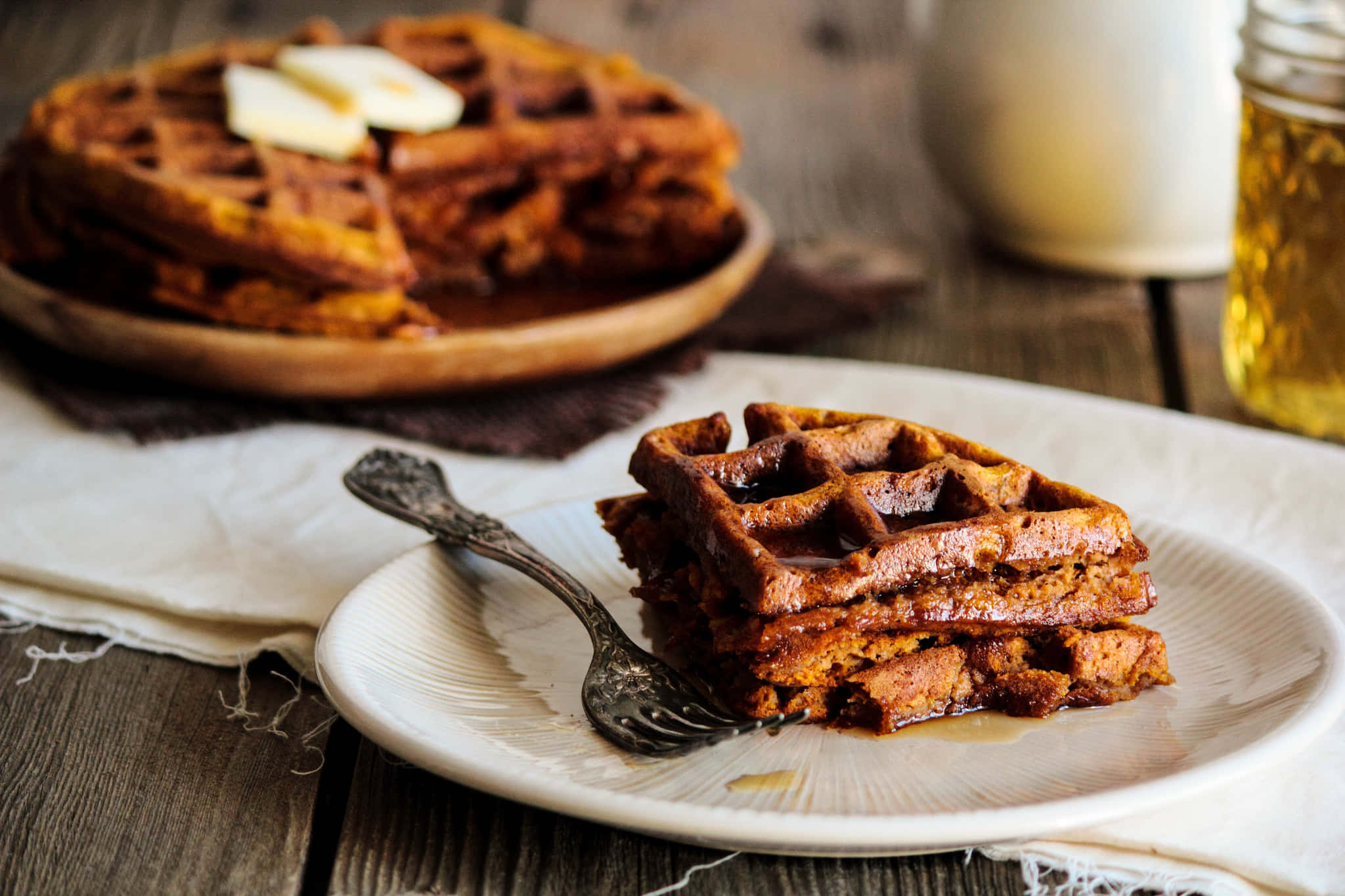 Waffle 桌布 壁紙 — 金黃色的南瓜鬆餅疊放在盤子上，配上奶油和糖漿，置於鄉村風木桌上。