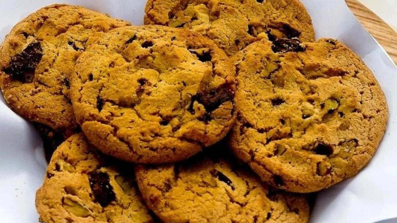 720p Cookies 桌布 壁紙 — 金黃色的巧克力曲奇堆放在一個鋪有白紙的碗中，可見巧克力和堅果塊。