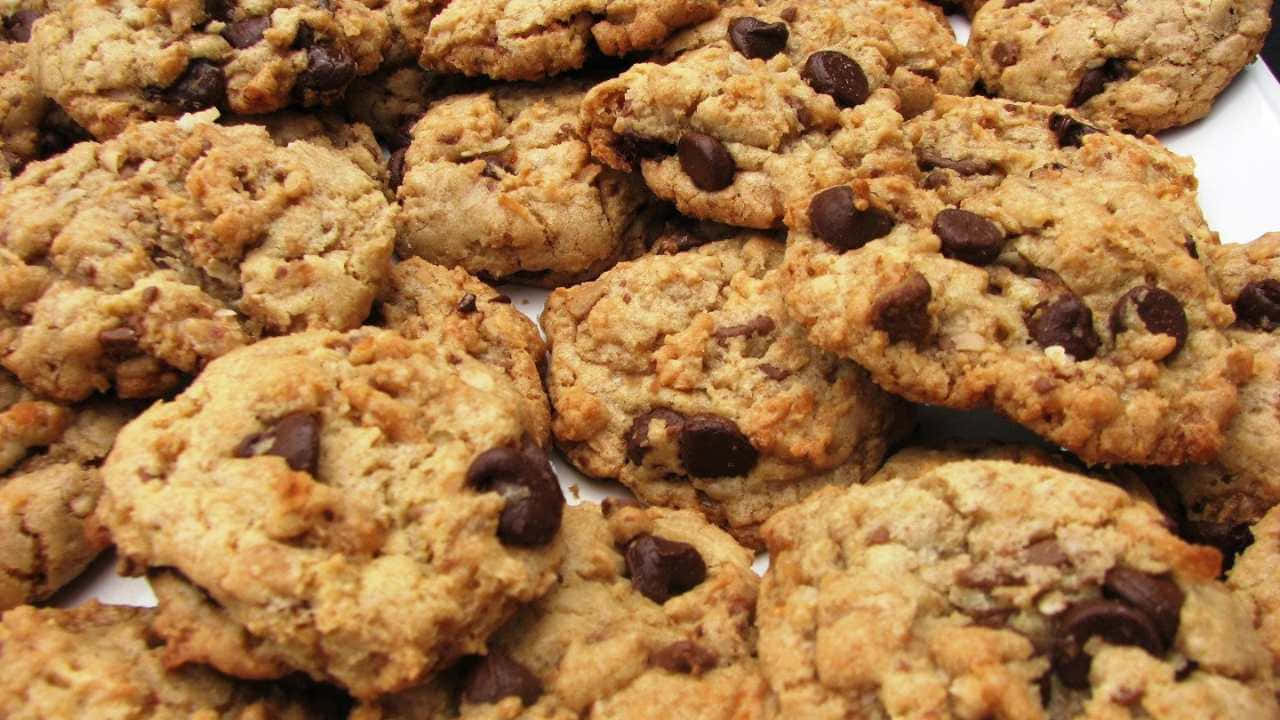720p Cookies 桌布 壁紙 — 金黃色的巧克力曲奇餅高高堆起，帶有融化的巧克力粒和可見的燕麥的特寫。