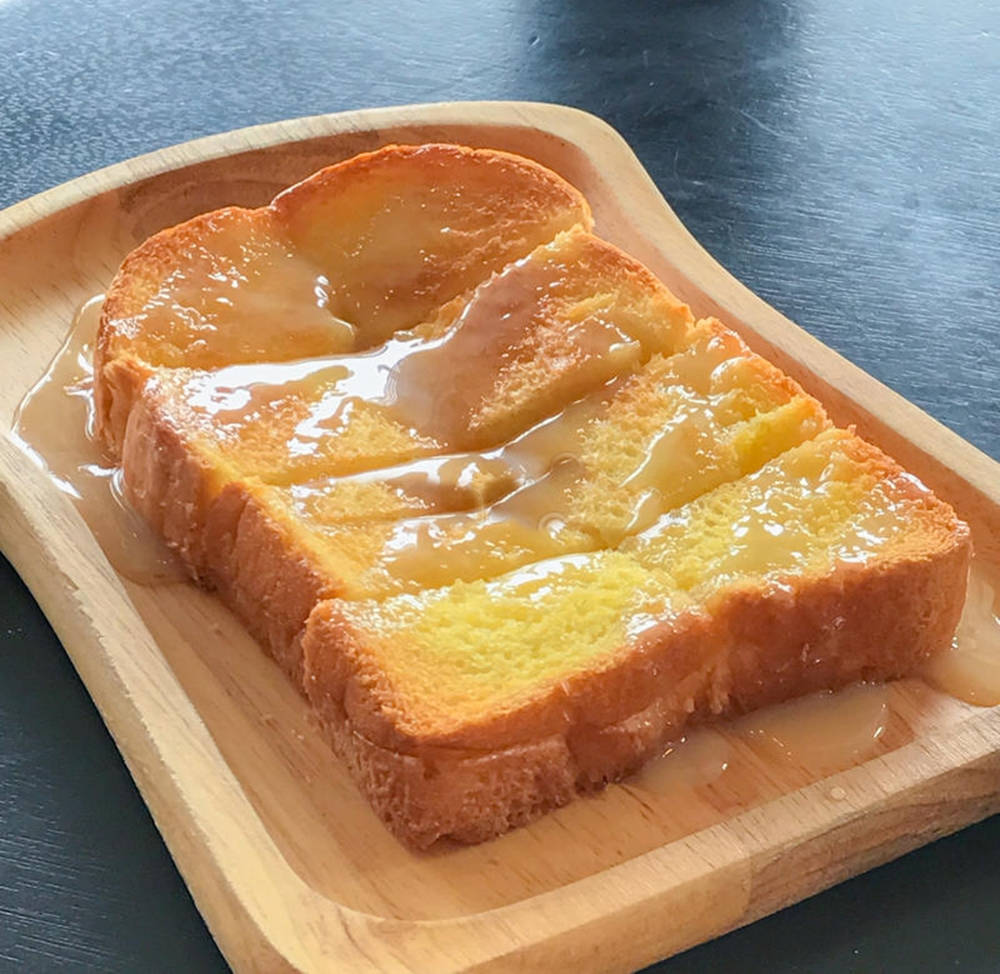 toast 桌布 壁紙 — 金黃色的法式吐司片在深色表面的木托盤上閃爍著糖漿。