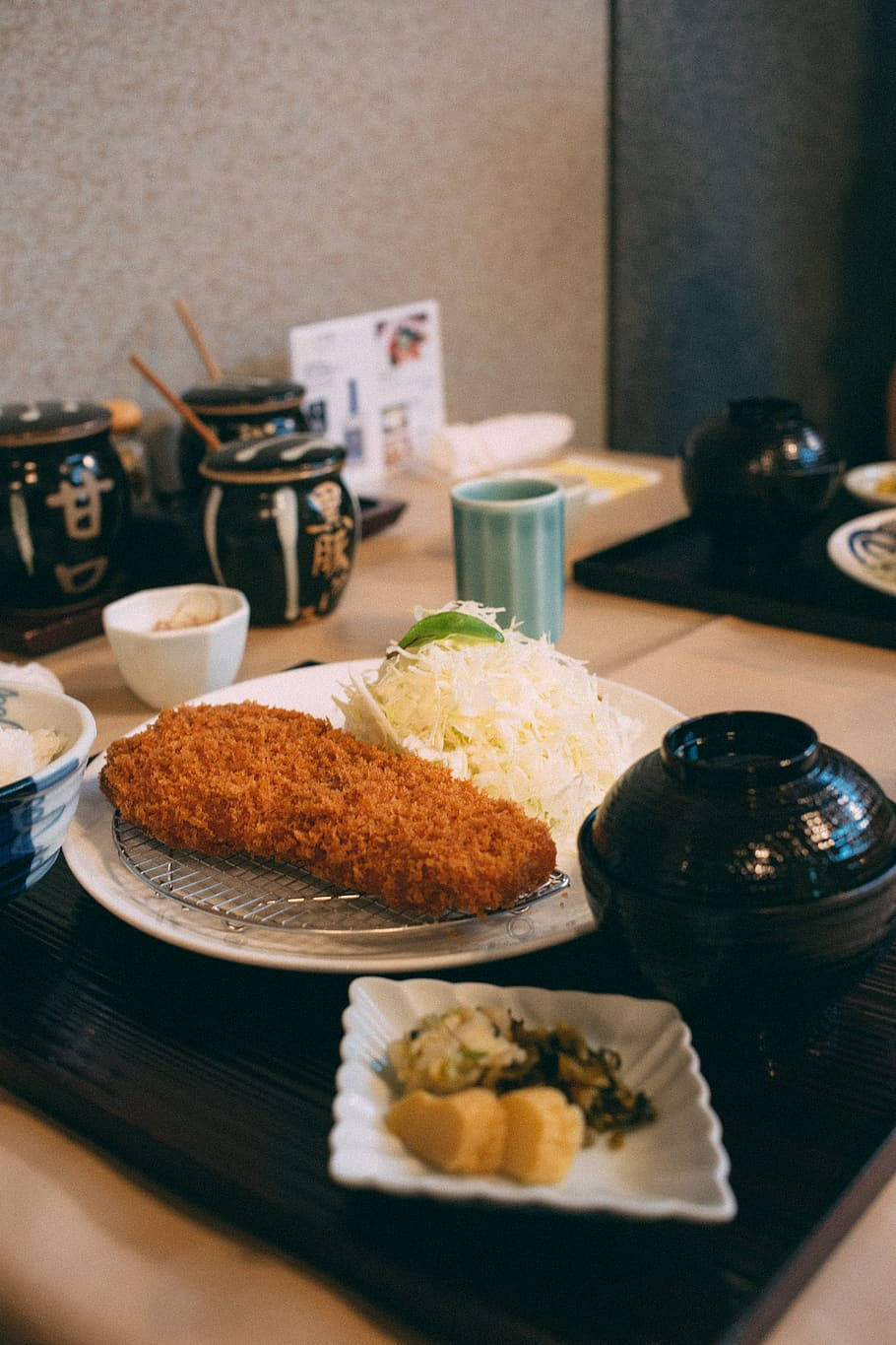 Food Photography 桌布 壁紙 — 金黃色的炸豬排配上高麗菜絲和配菜，放在傳統日本餐廳的木托盤上。