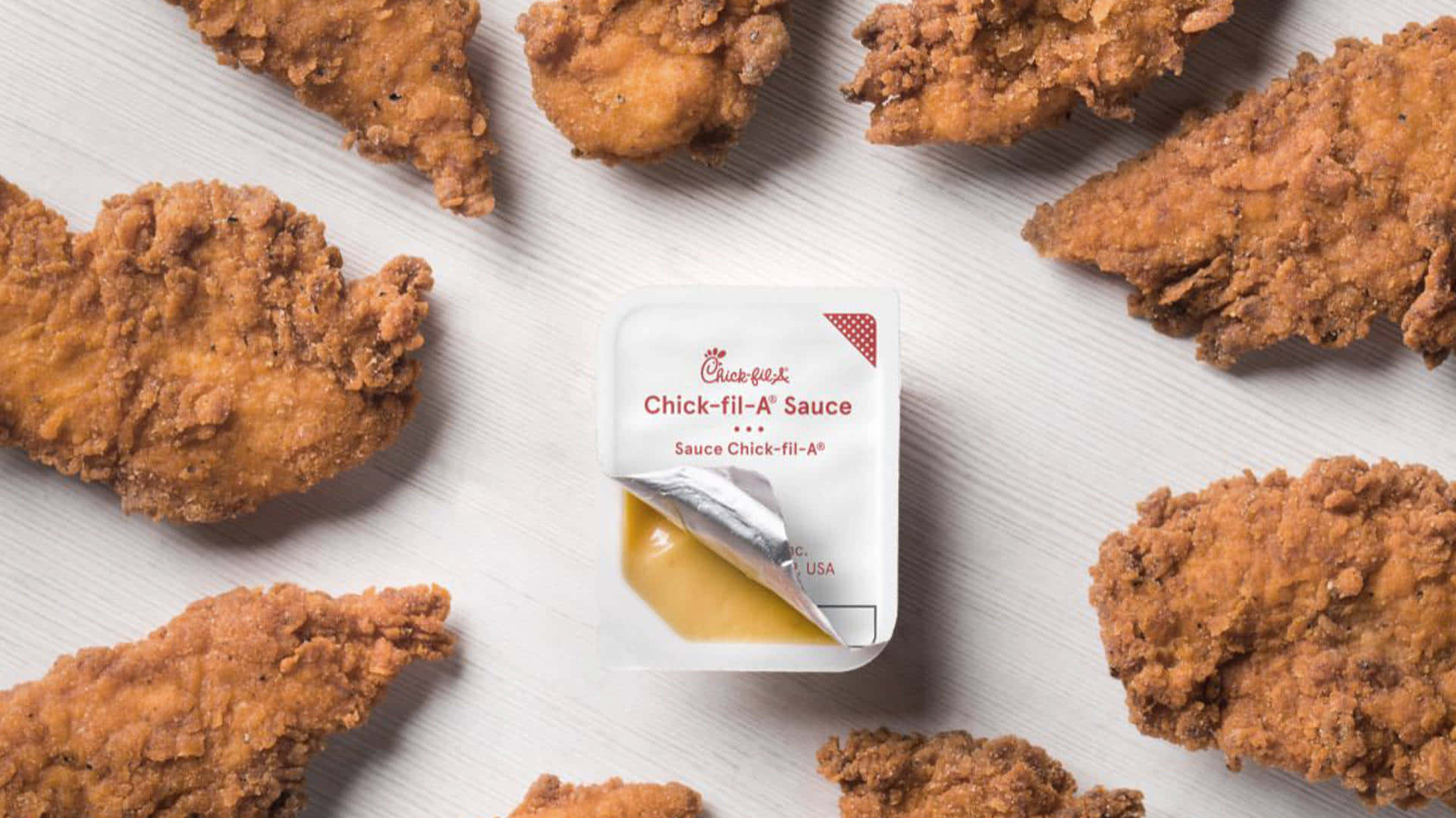 Chicken 桌布 壁紙 — 金黃色的炸雞塊圍繞著一個Chick-fil-A醬料包在淺色木質表面上。