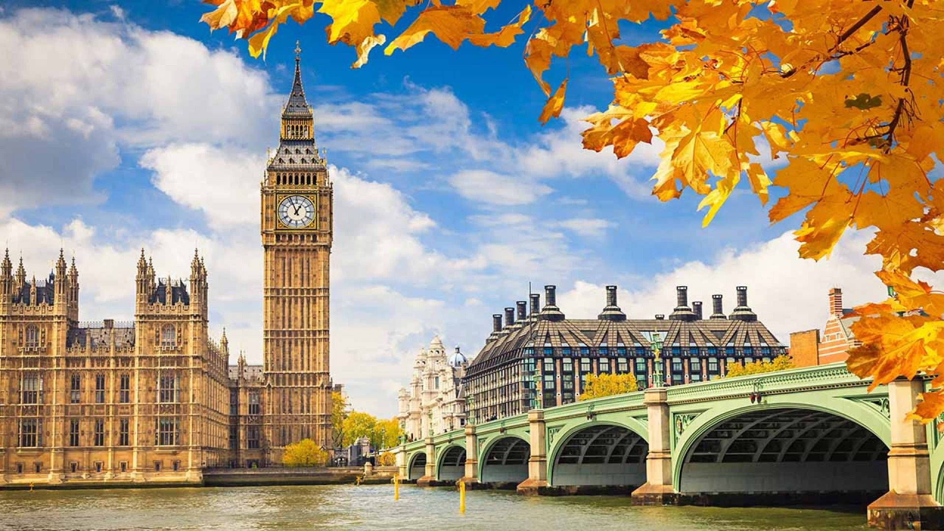 Europe 桌布 壁紙 — 金黃色的秋葉框住了泰晤士河上標誌性的伊麗莎白塔和西敏橋上方的明亮藍天。