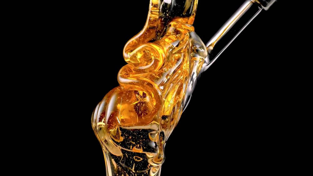 Honeycomb 桌布 壁紙 — 金黃色的蜂蜜從玻璃滴管中濃稠地滴下，在純黑背景上展現其黏稠質感。