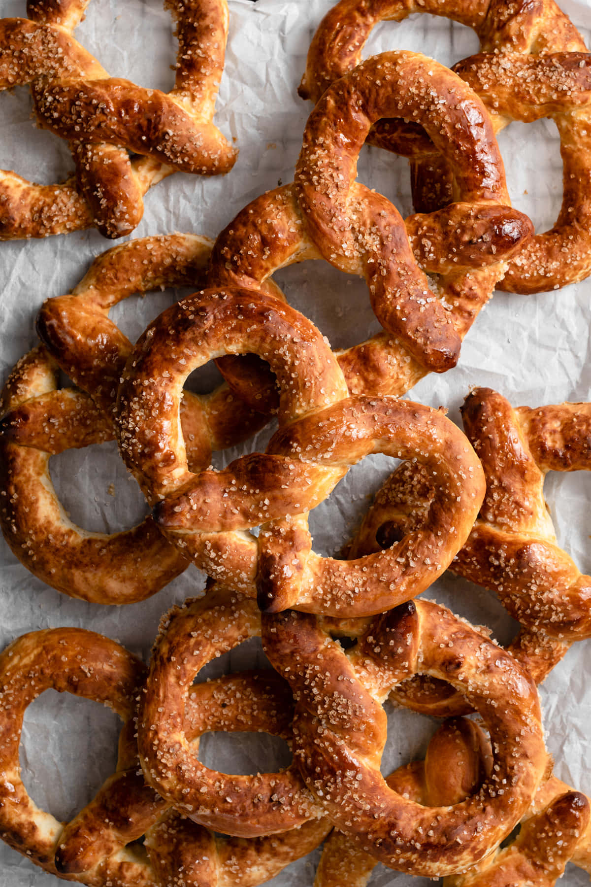 Pretzel 桌布 壁紙 — 金黃色的蝴蝶餅配粗鹽，在皺巴巴的烘焙紙上閃閃發光，以特寫俯拍鏡頭拍攝。