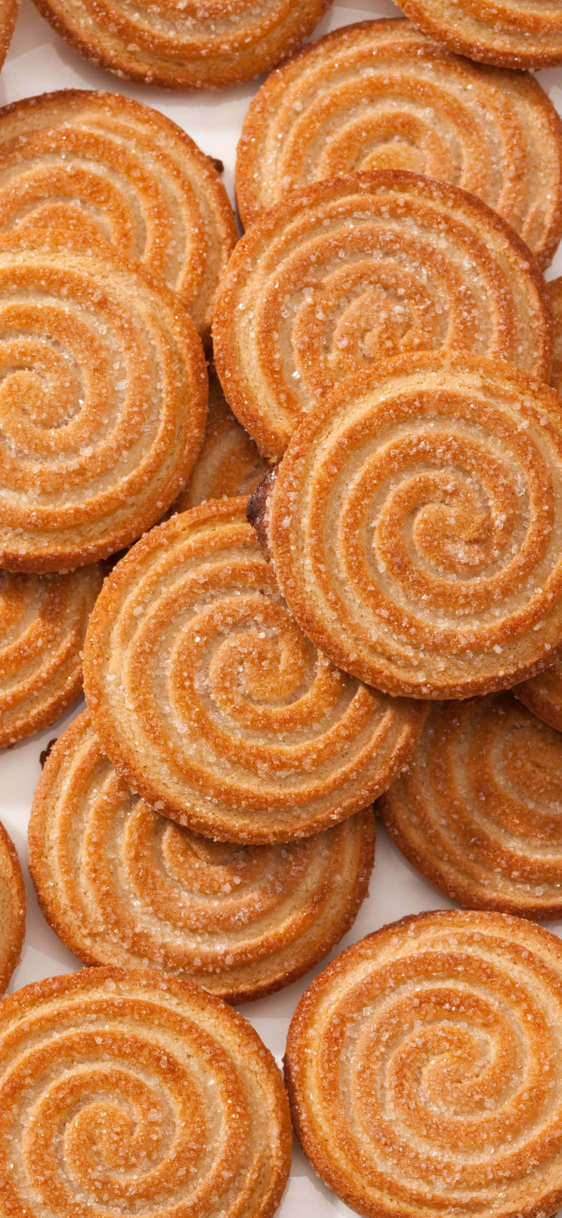 Pastries 桌布 壁紙 — 金黃色的螺旋餅乾撒上糖粉，堆疊在白色表面上。