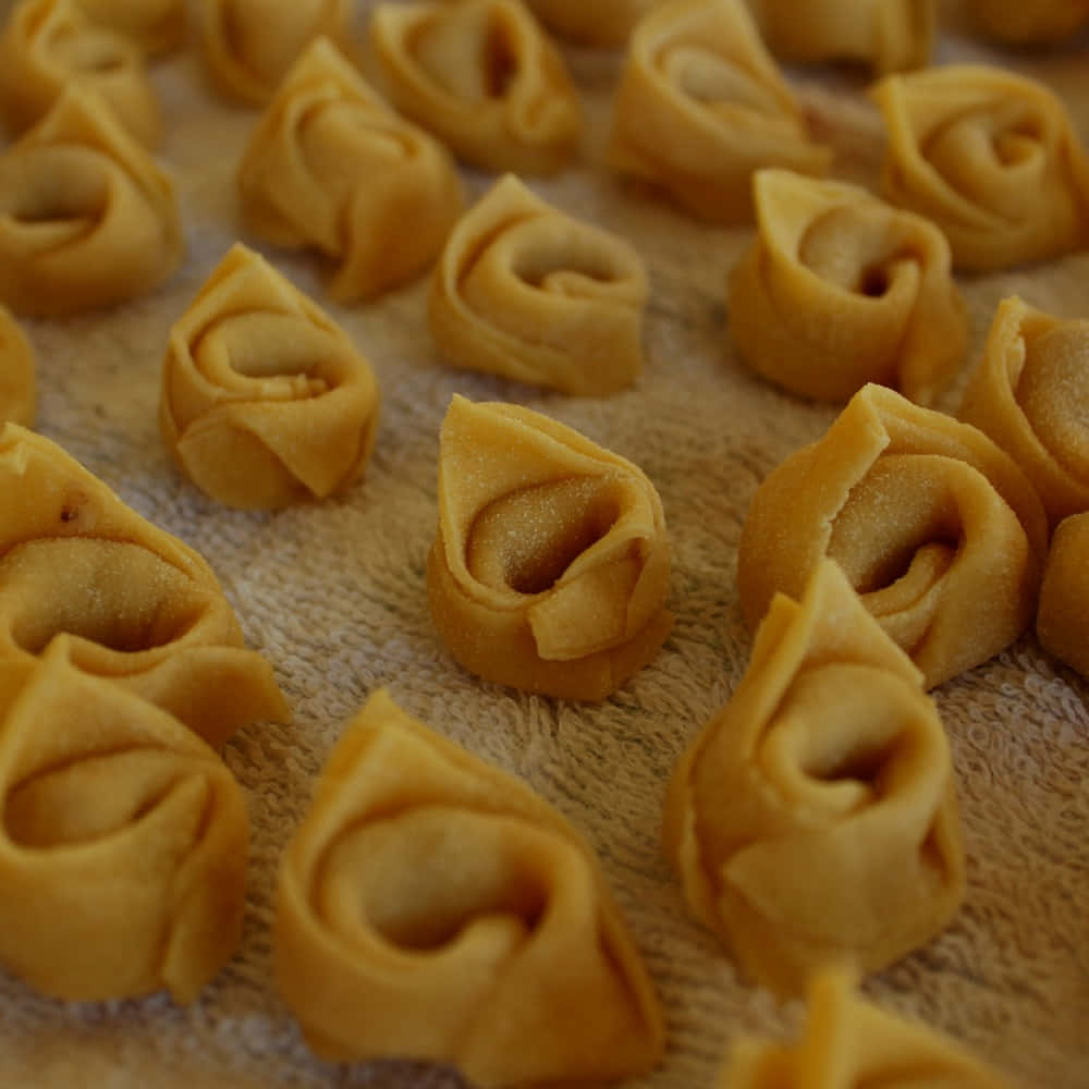 Pasta 桌布 壁紙 — 金黃色的餃子帶有細緻的褶皺，放在有紋理的毛巾上，沐浴在溫暖誘人的光線中。