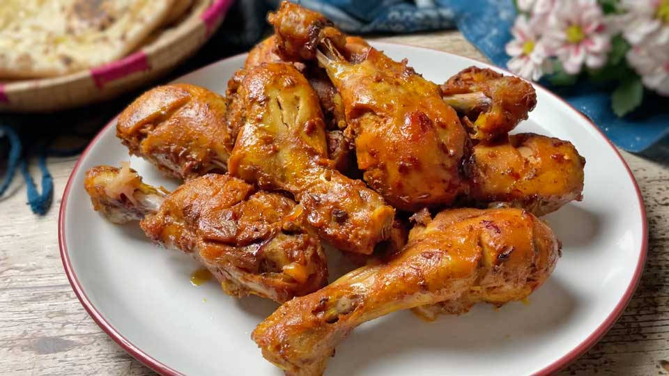 fried chicken 桌布 壁紙 — 金黃色的香料雞腿在帶有紅色邊緣的白色盤子上閃閃發光，旁邊有扁麵包和粉紅色的花朵。