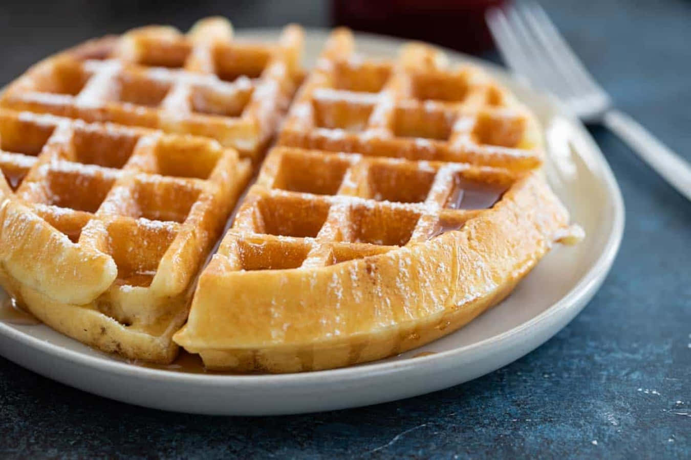 Waffle 桌布 壁紙 — 金黃色的鬆餅撒上糖粉並淋上糖漿，誘人地放在白色盤子上。