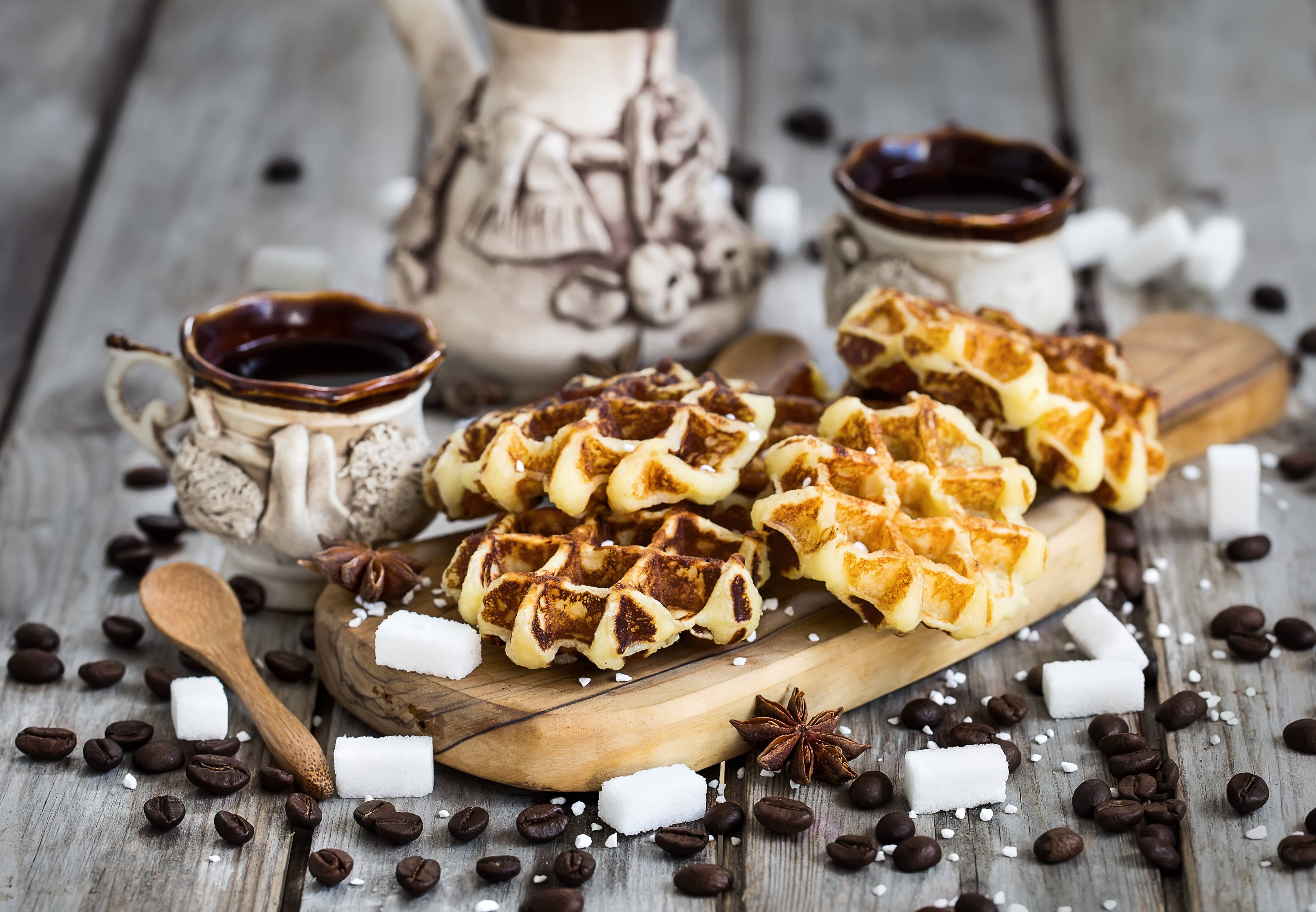 Waffle 桌布 壁紙 — 金黃色的鬆餅配上巧克力醬和方糖，放在木板上，周圍有咖啡豆和八角，置於鄉村風格的木桌上。