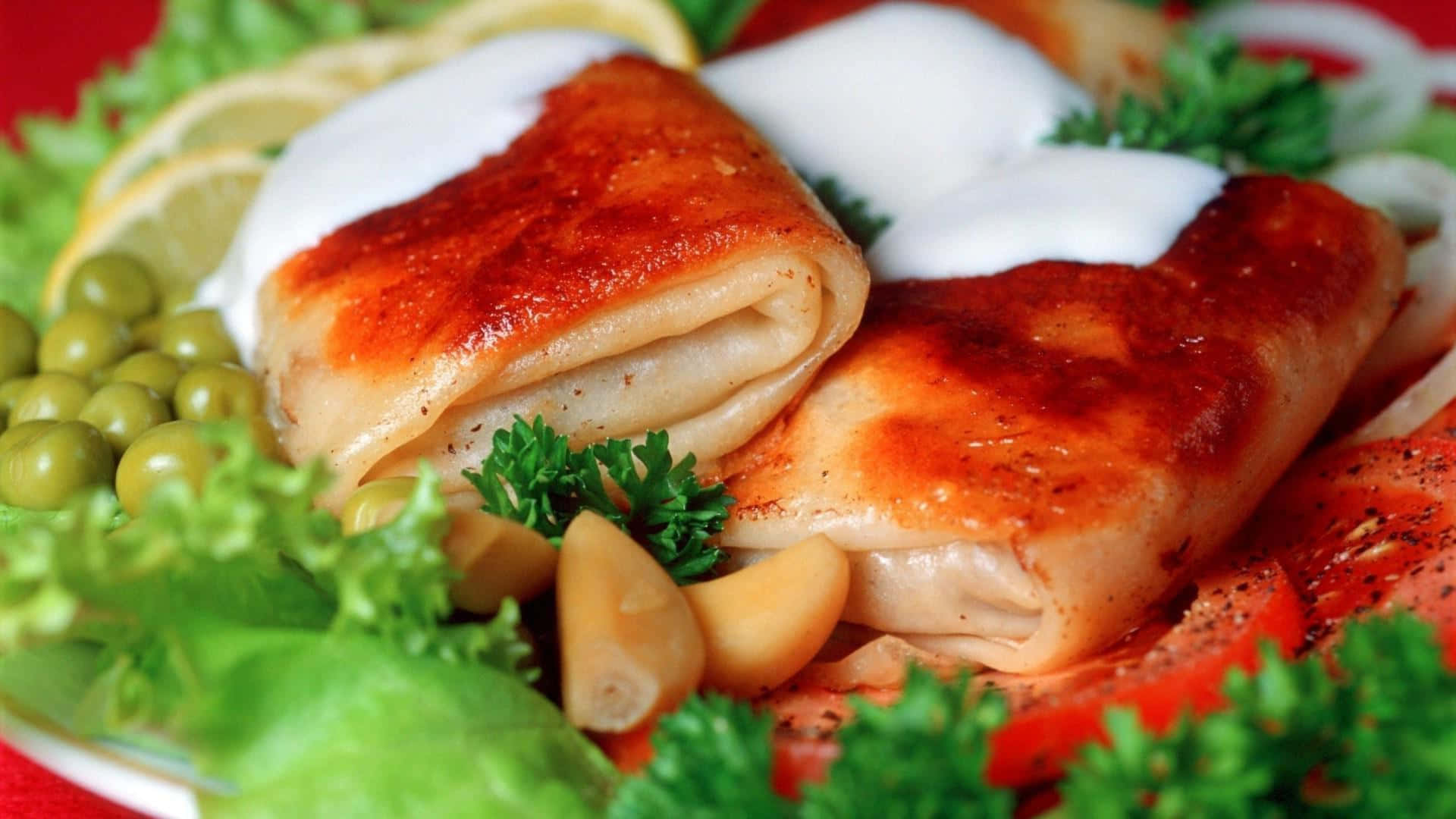 食物動圖 桌布 壁紙 — 金黃色的魚柳卷，上面淋上奶油醬汁，用新鮮歐芹、檸檬片和青豆裝飾，放在鮮紅色的盤子上。