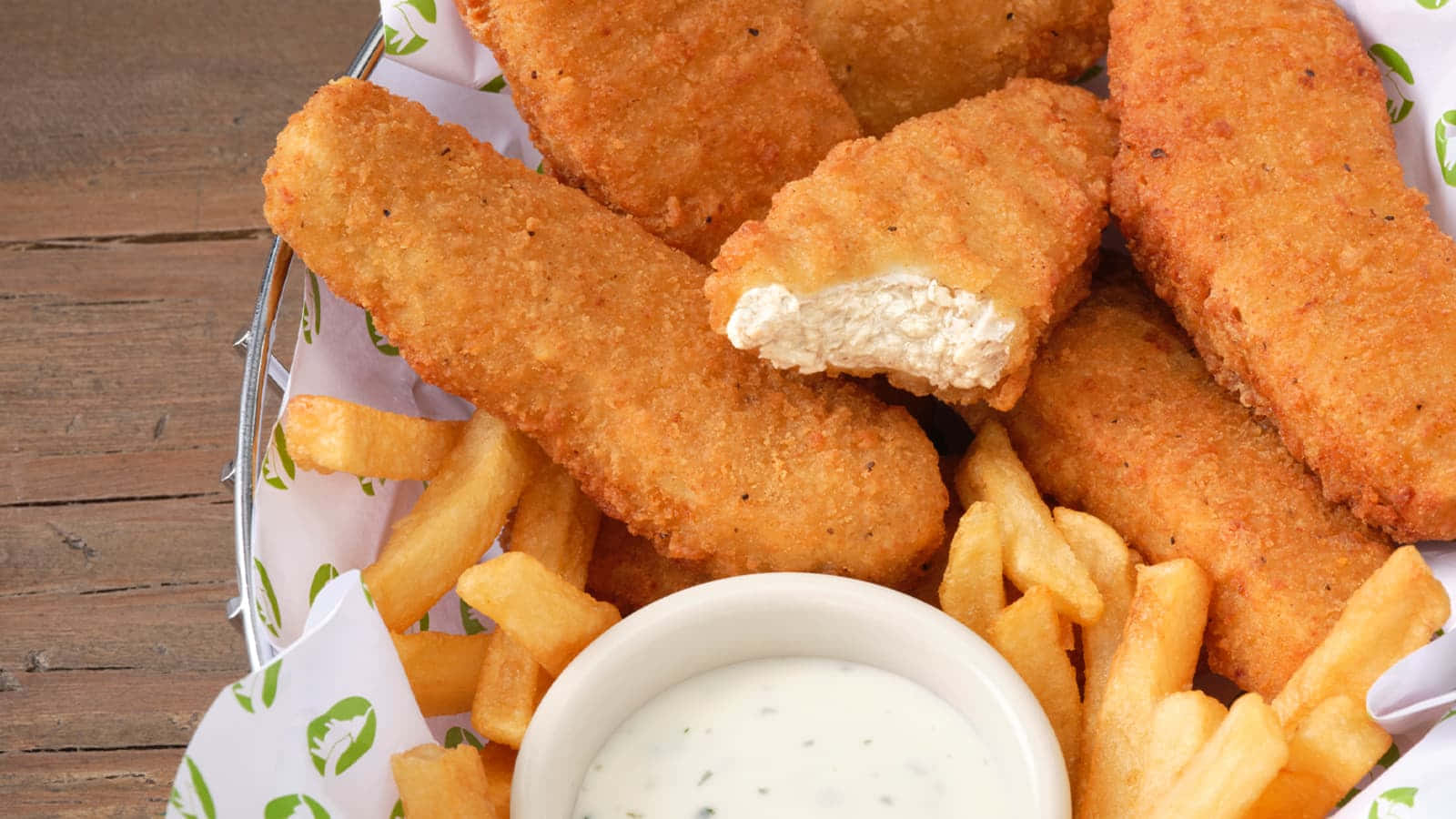 Fries 桌布 壁紙 — 金黃色的魚條和香脆薯條放在鐵絲籃裡，配上奶油狀的塔塔醬，擺在質樸的木桌上。