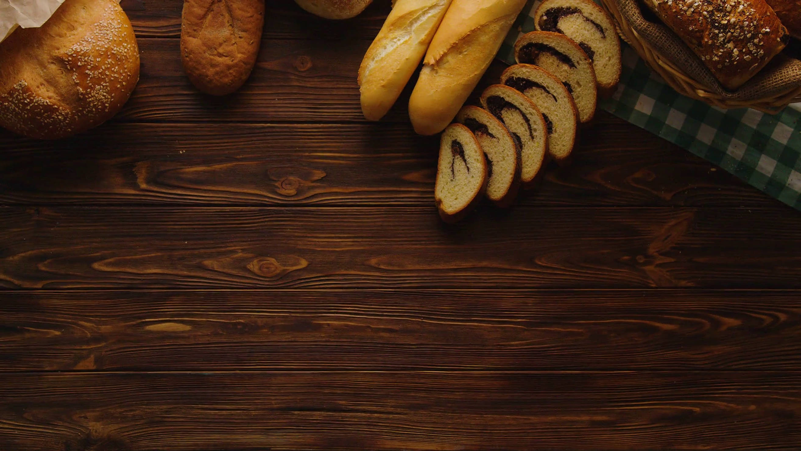 Bakery 桌布 壁紙 — 金黃色的麵包和切片麵包放在鋪有綠色格紋布的深色木桌上。