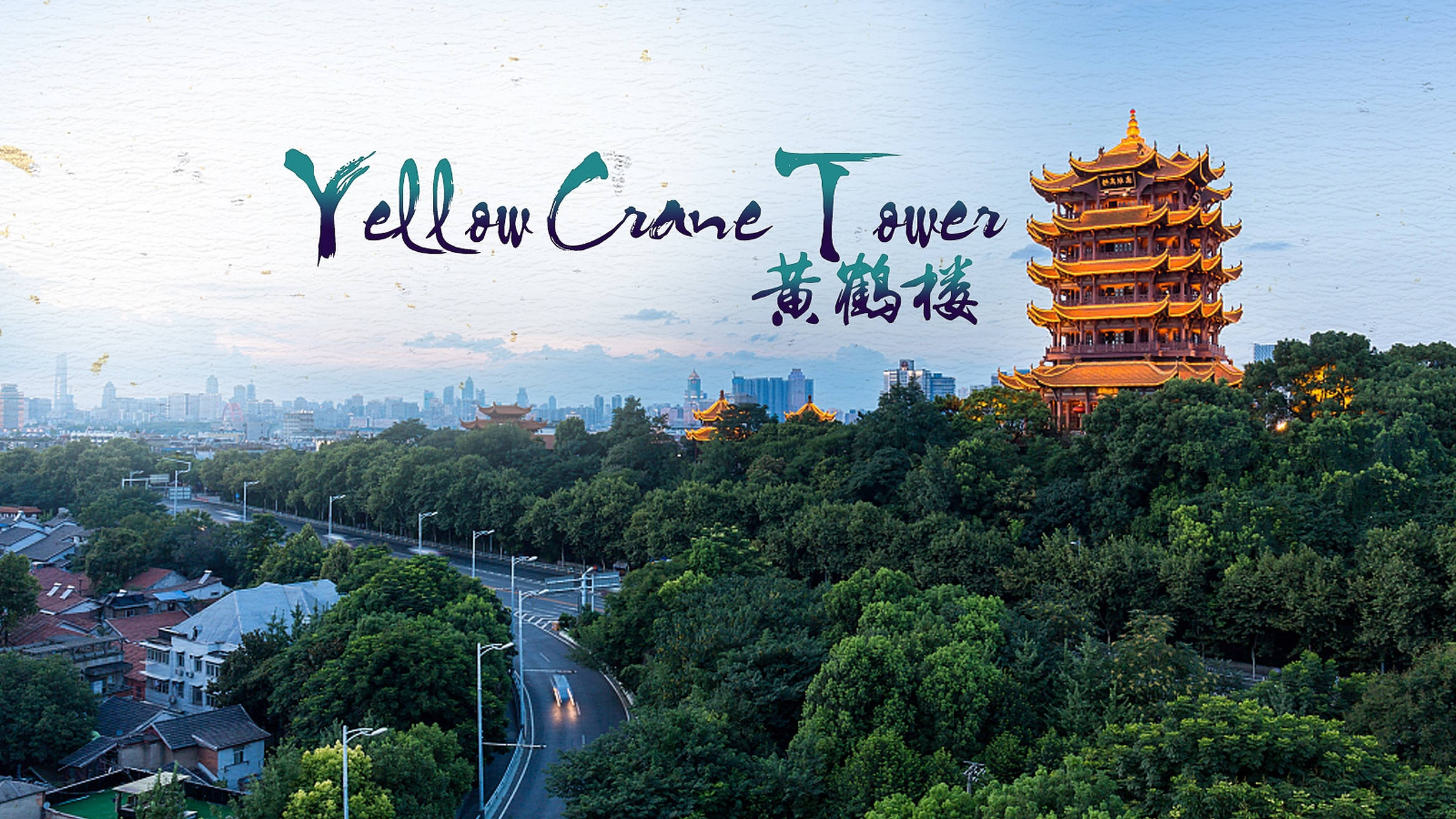 Wuhan 桌布 壁紙 — 金黃色的黃鶴樓聳立在茂密的綠樹之上，暮色中隱約可見現代城市的天際線。