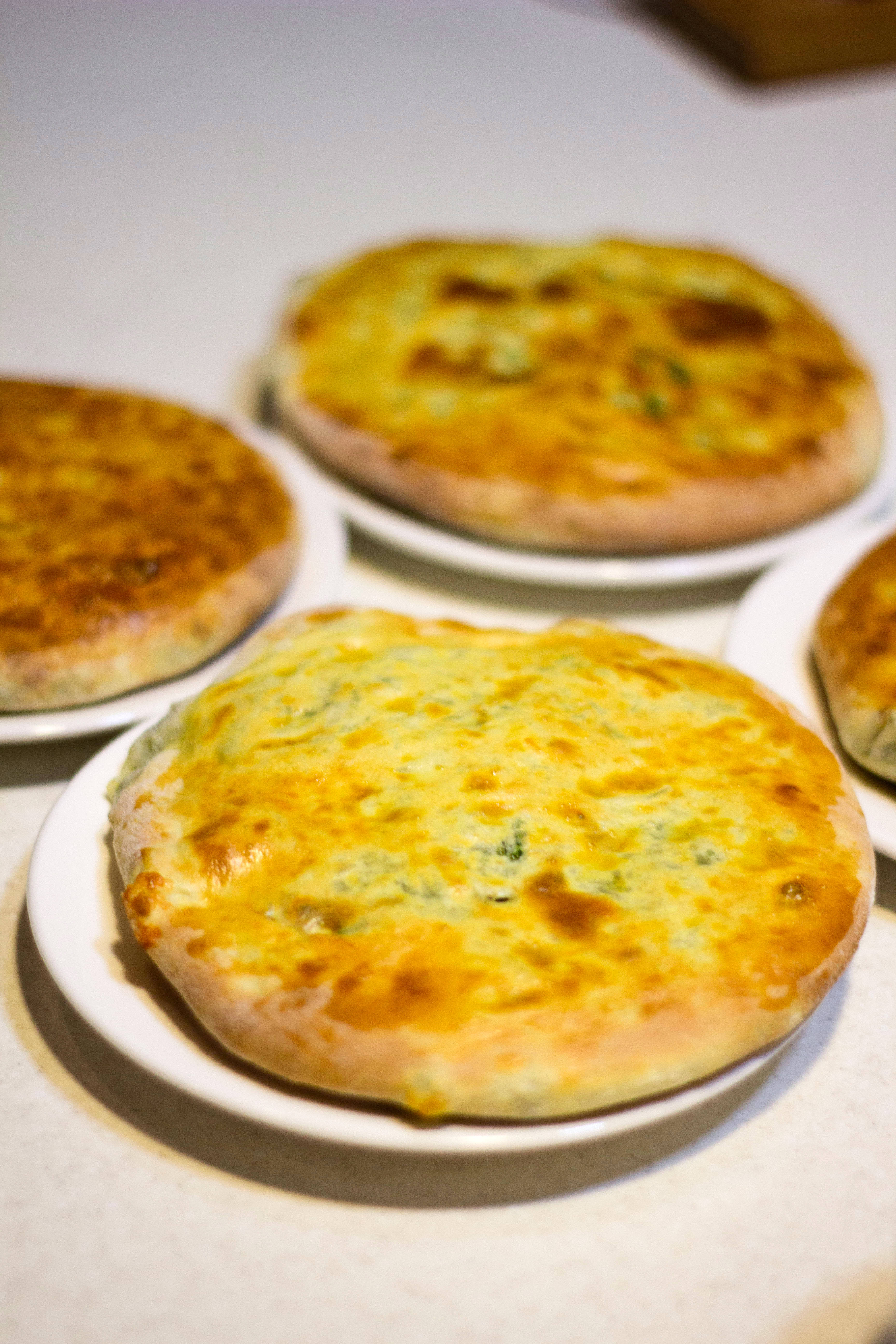 Cheese 桌布 壁紙 — 金黃色起司餡餅放在白色盤子上，置於淺色檯面上，背景柔和模糊。