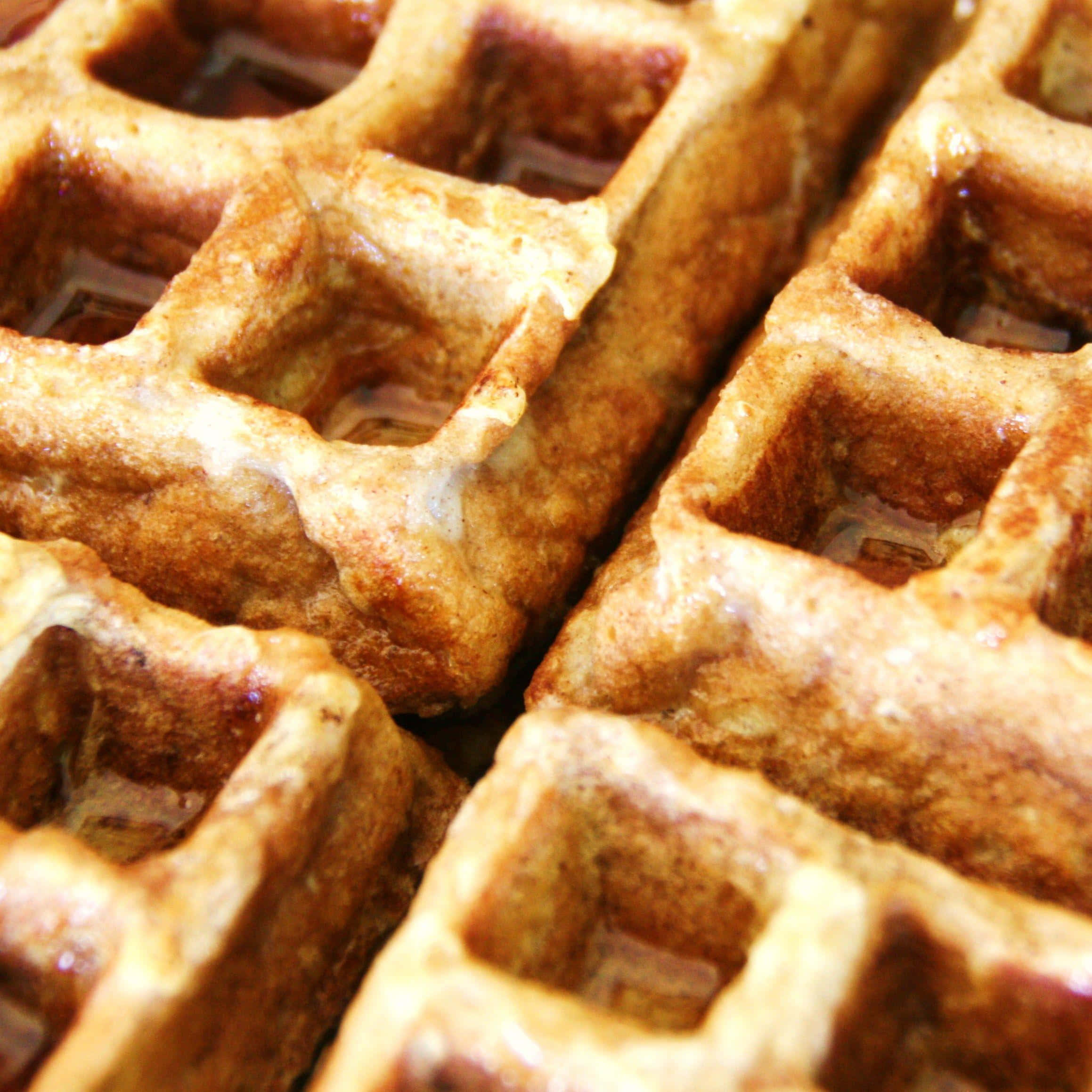 Waffle 桌布 壁紙 — 金黃色鬆餅在特寫鏡頭中閃爍著糖漿，突顯其酥脆質感。