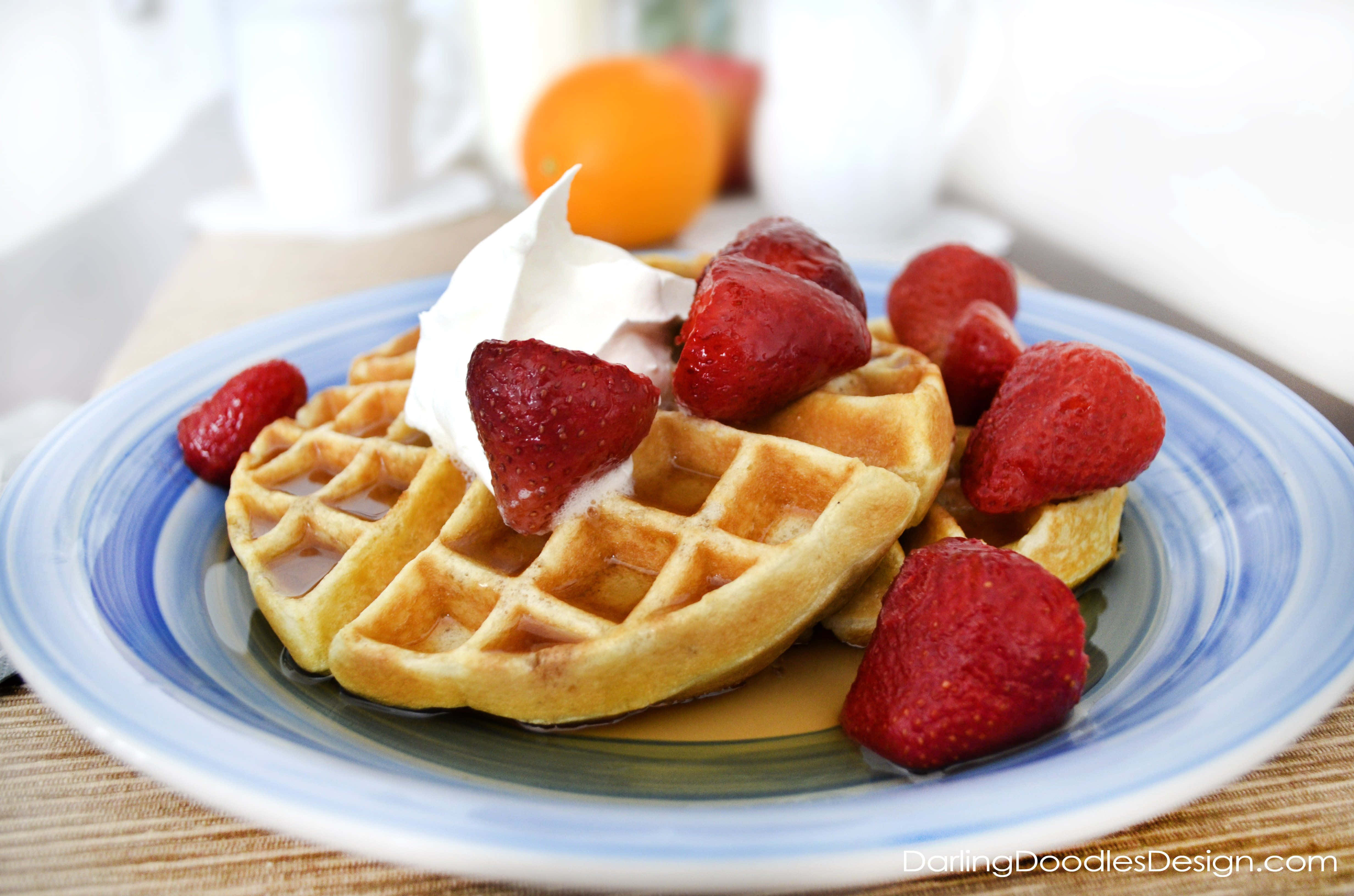 Waffle 桌布 壁紙 — 金黃色鬆餅搭配新鮮草莓、鮮奶油和糖漿，放在藍色條紋盤子上。