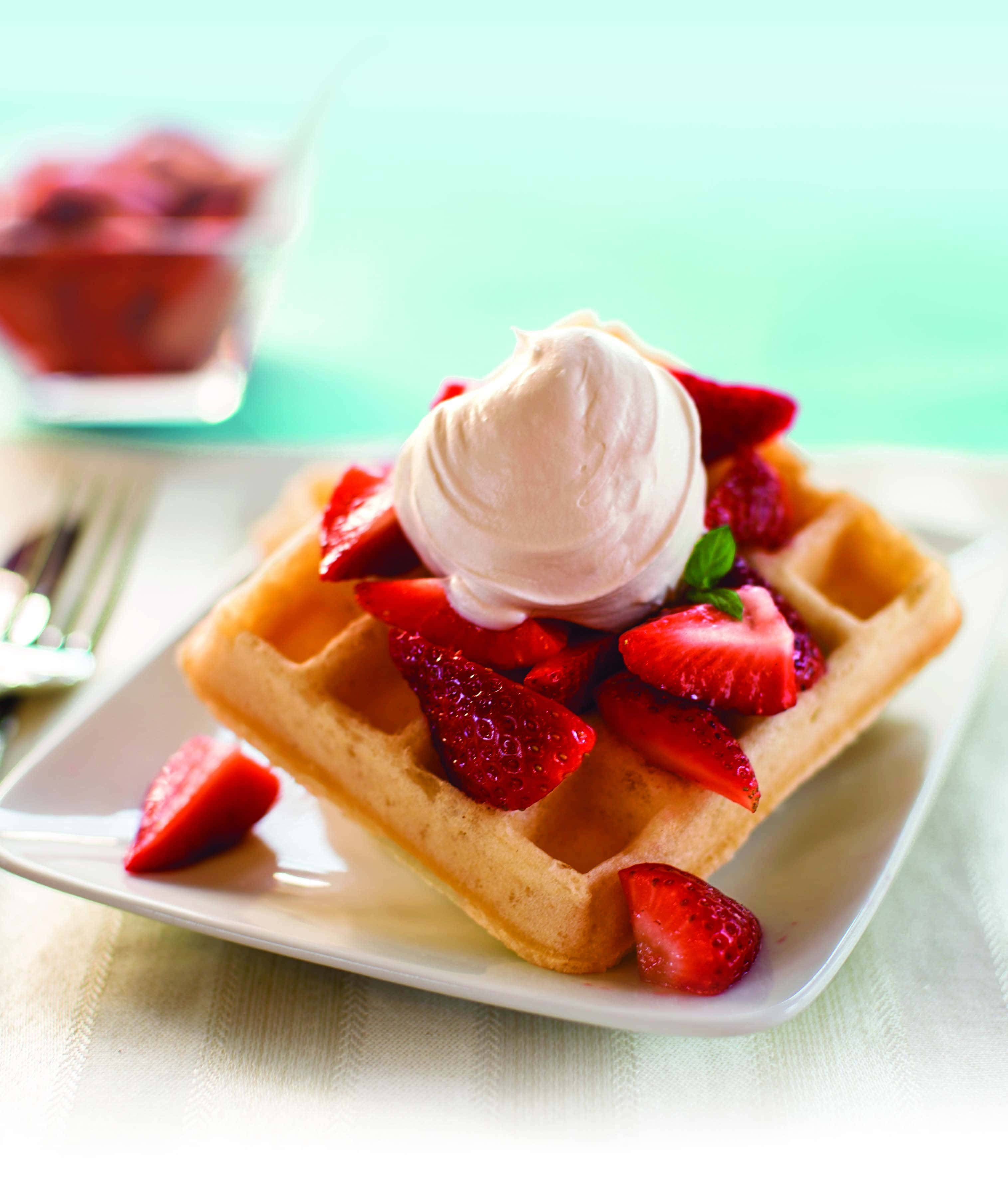 Waffle 桌布 壁紙 — 金黃色鬆餅搭配新鮮草莓和一球鮮奶油，放在白色盤子上。