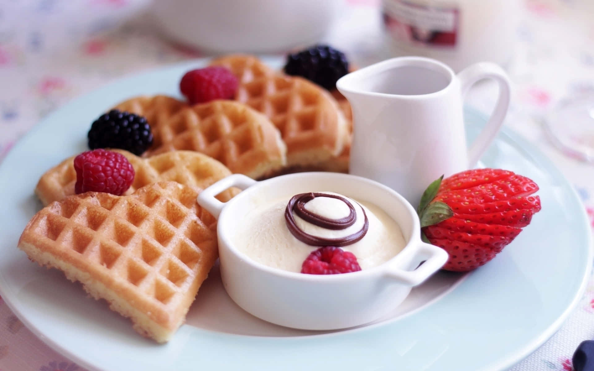 Waffle 桌布 壁紙 — 金黃色鬆餅搭配新鮮莓果和帶有巧克力漩渦的奶油甜點，放在淺藍色盤子上。