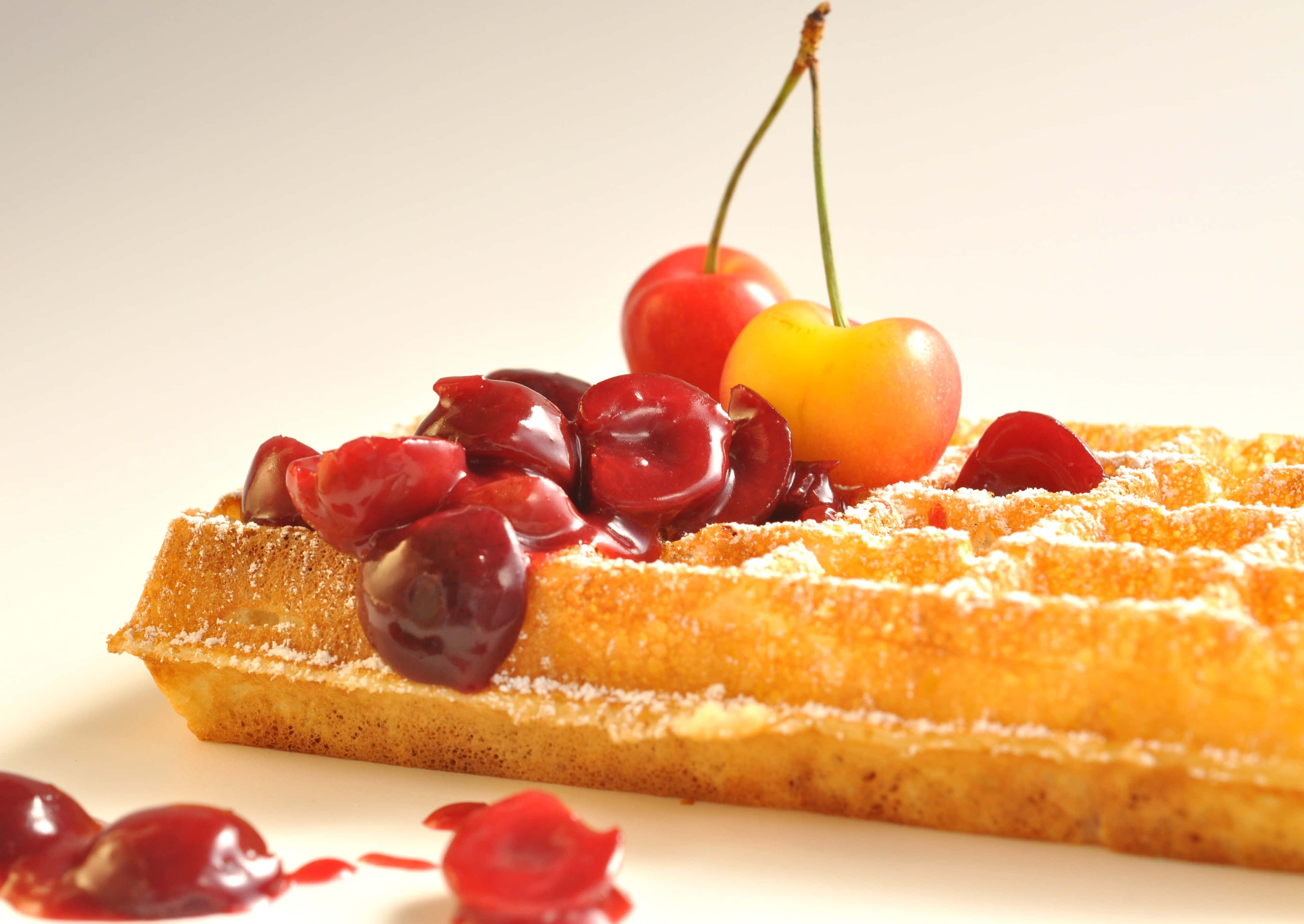 Waffle 桌布 壁紙 — 金黃色鬆餅撒上糖粉，上面放有光澤的櫻桃和糖漿，背景為純白色。