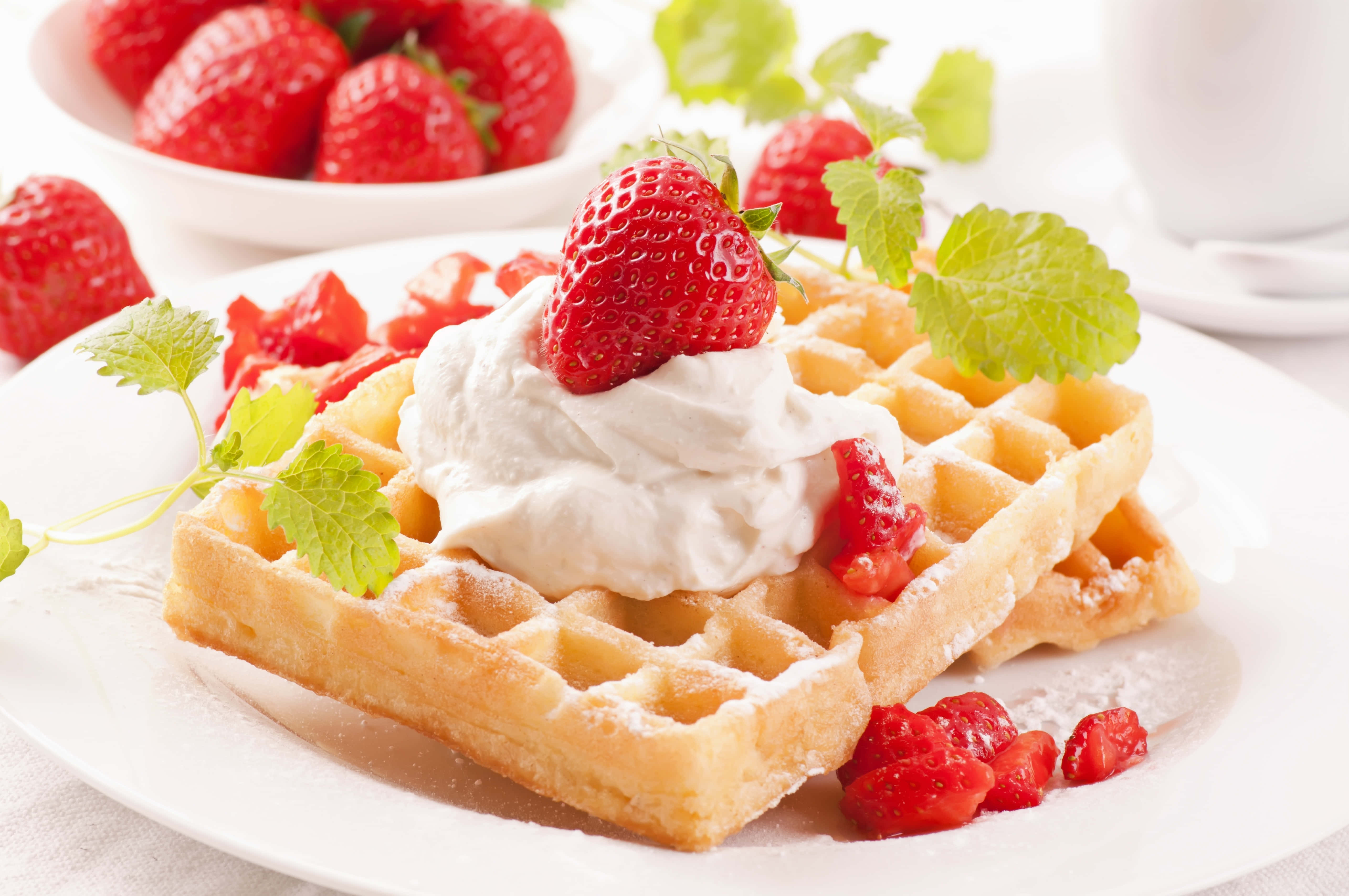 Waffle 桌布 壁紙 — 金黃色鬆餅撒上糖粉，搭配鮮奶油和新鮮草莓，並以薄荷葉裝飾。
