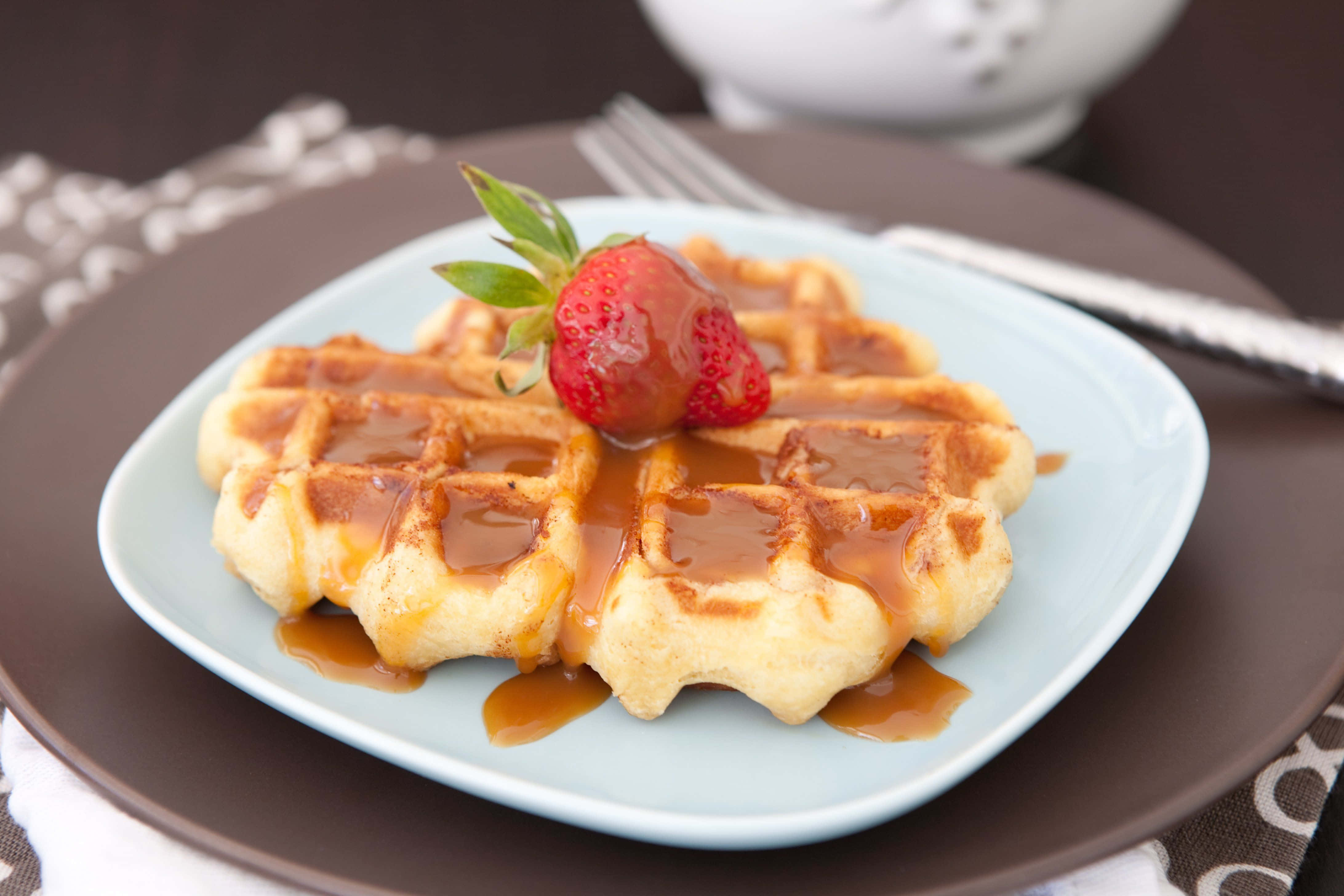 Waffle 桌布 壁紙 — 金黃色鬆餅淋上焦糖醬，配上新鮮草莓，放在淺藍色盤子上。