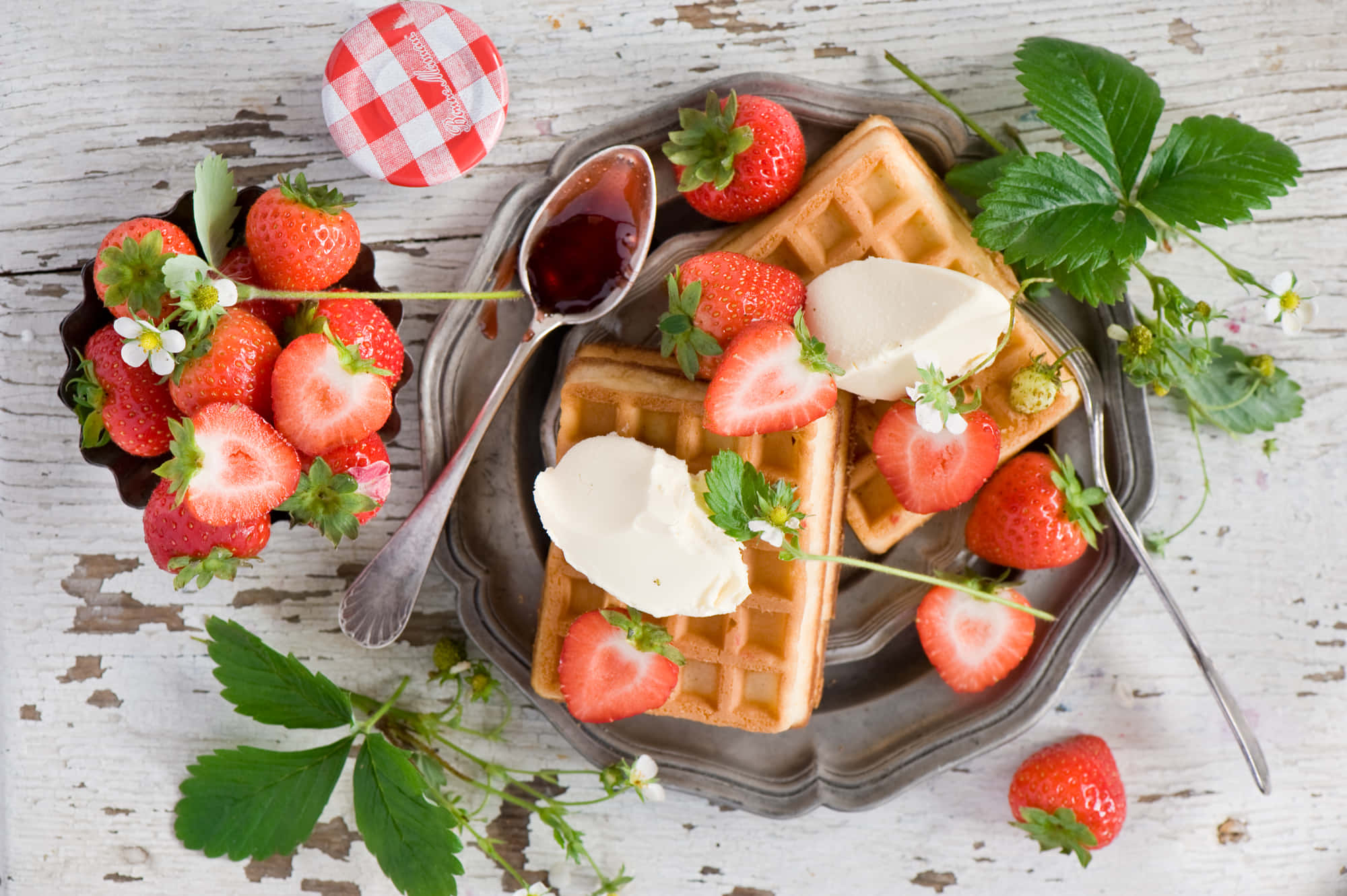 Waffle 桌布 壁紙 — 金黃色鬆餅配上新鮮草莓和鮮奶油，放在質樸的金屬盤上，旁邊有一個復古格紋蓋子。