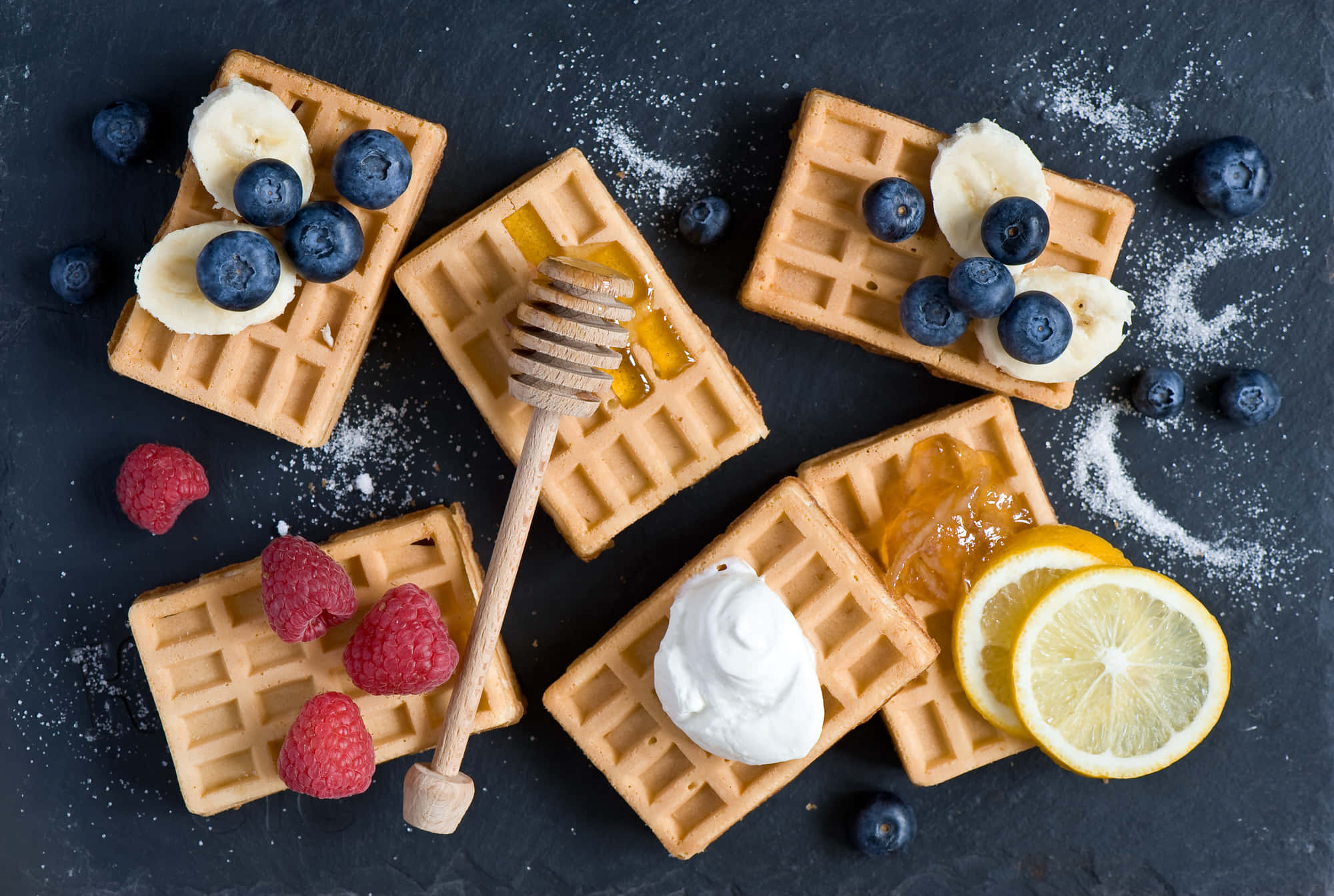Waffle 桌布 壁紙 — 金黃色鬆餅配上莓果、蜂蜜和鮮奶油，擺放在深色石板表面上。