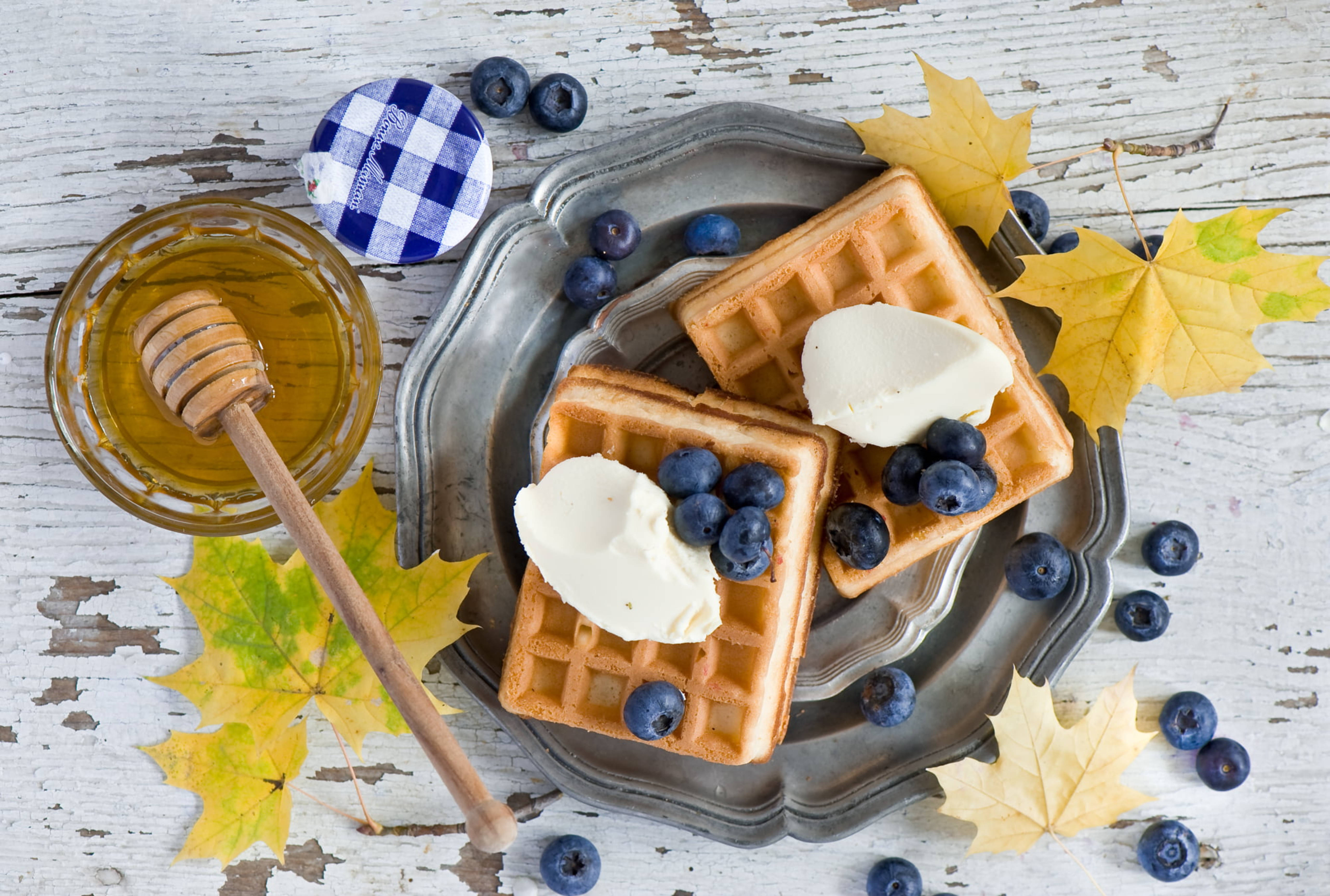 Waffle 桌布 壁紙 — 金黃色鬆餅配上鮮奶油和藍莓，放在復古托盤上，旁邊有蜂蜜和秋葉。