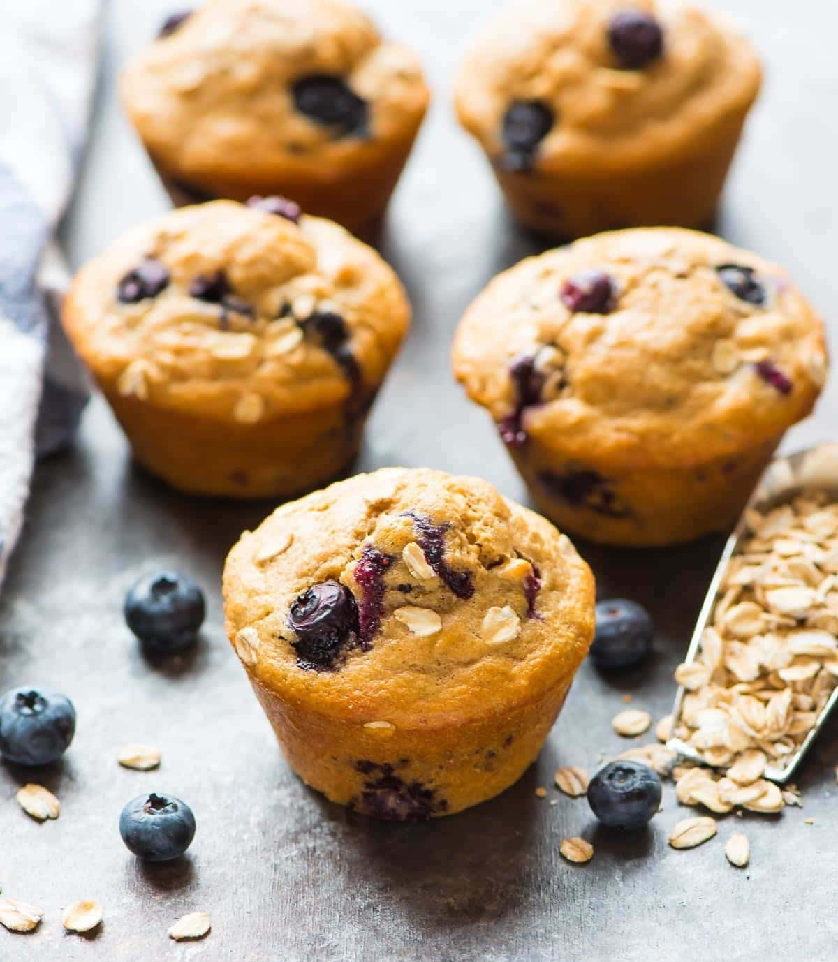 Blueberry Muffins 桌布 壁紙 — 金黃藍莓燕麥馬芬，新鮮莓果和燕麥片散落在質樸的金屬表面上。