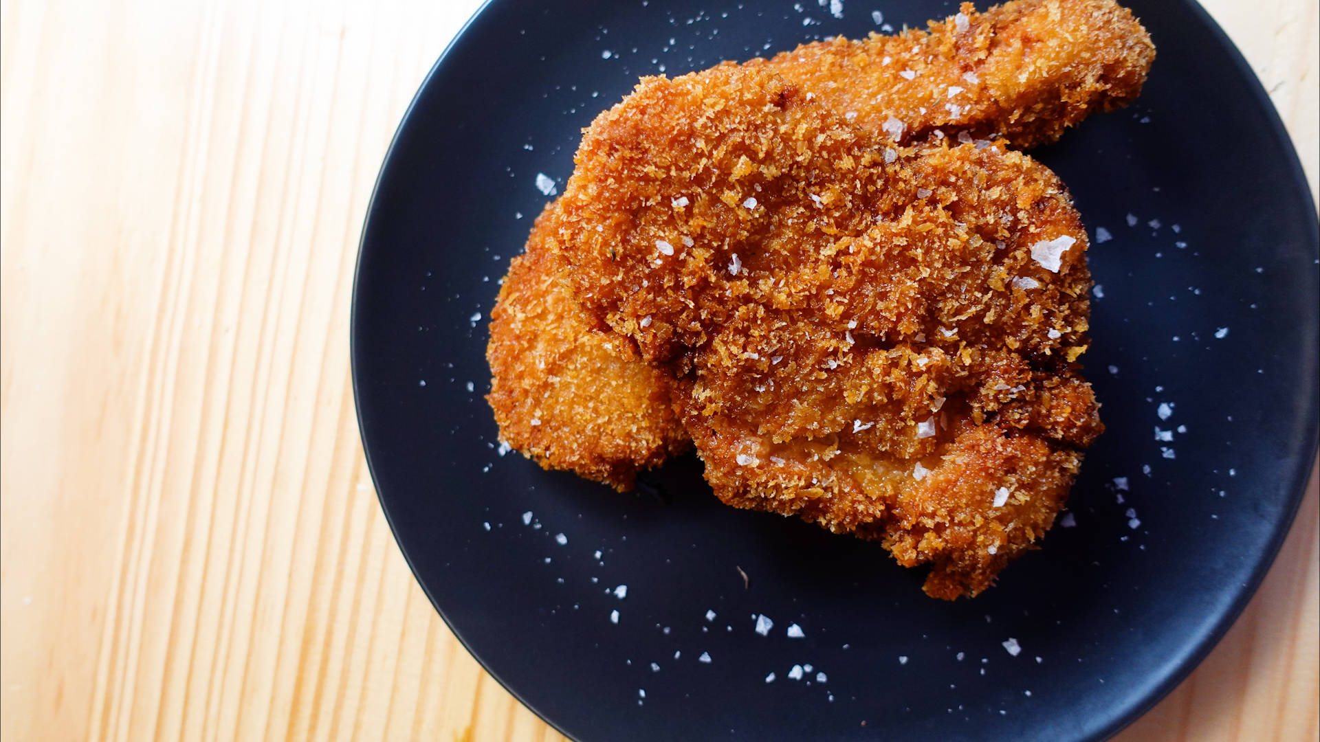 Food Photography 桌布 壁紙 — 金黃酥脆的炸雞塊配上粗鹽，放在淺色木質表面上的斑點黑盤上。