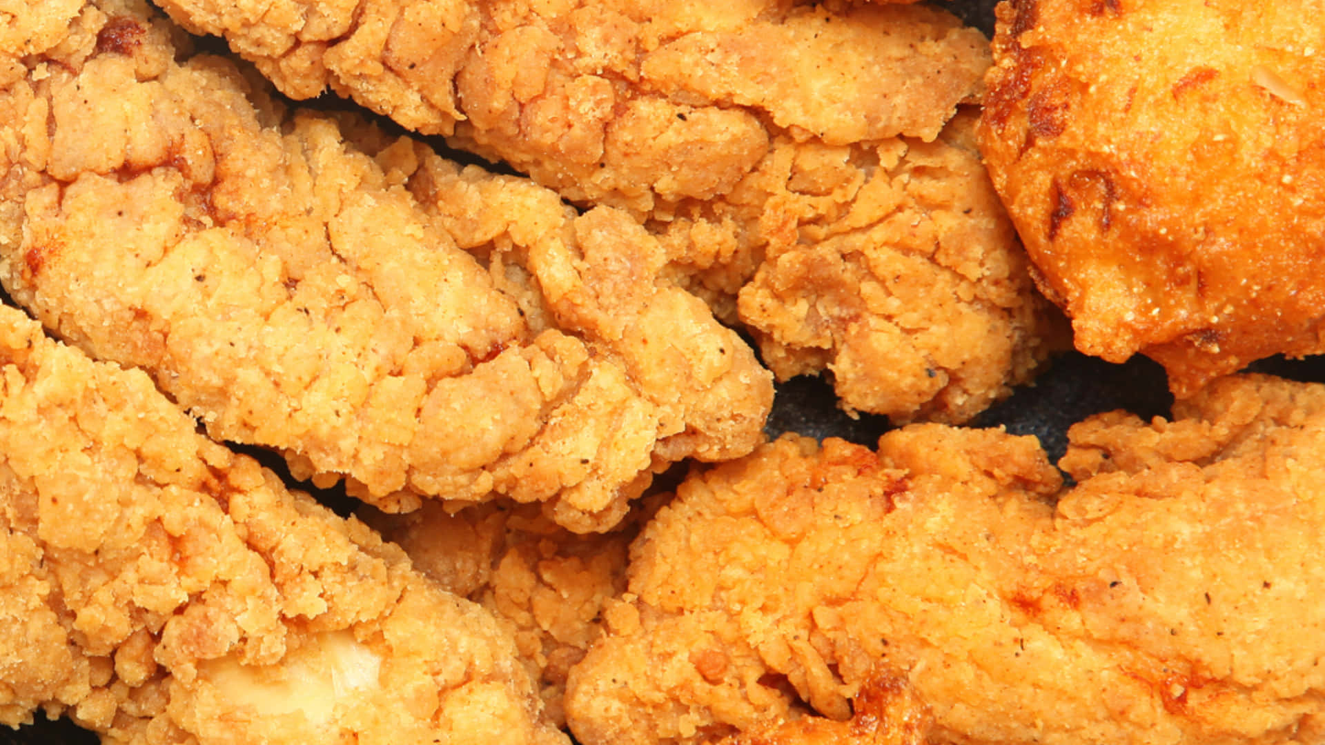 fried chicken 桌布 壁紙 — 金黃酥脆的炸雞條高高堆起，帶有質感的麵包粉和調味料斑點。