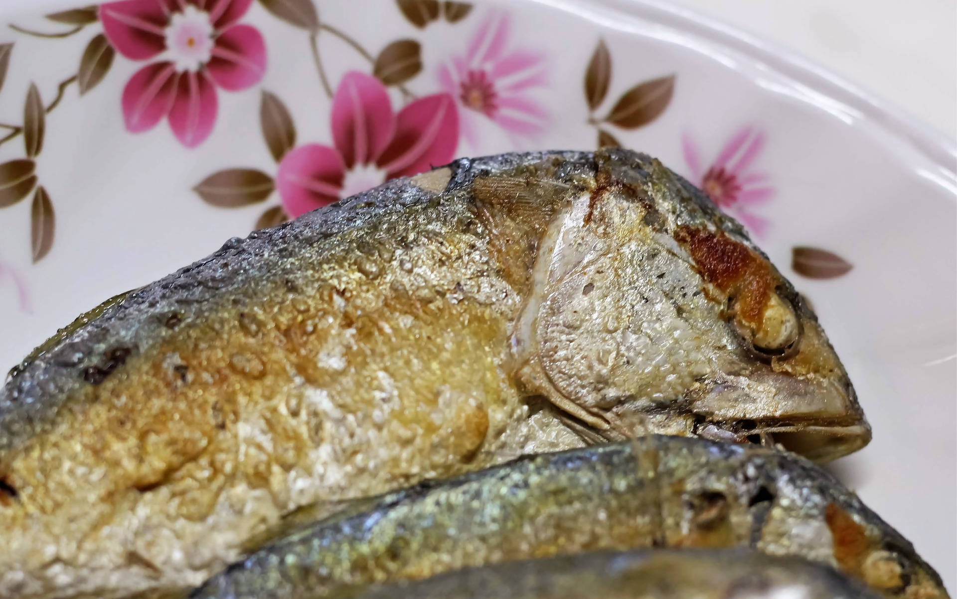 魚 桌布 壁紙 — 金黃酥脆的炸魚放在花卉圖案的盤子上。